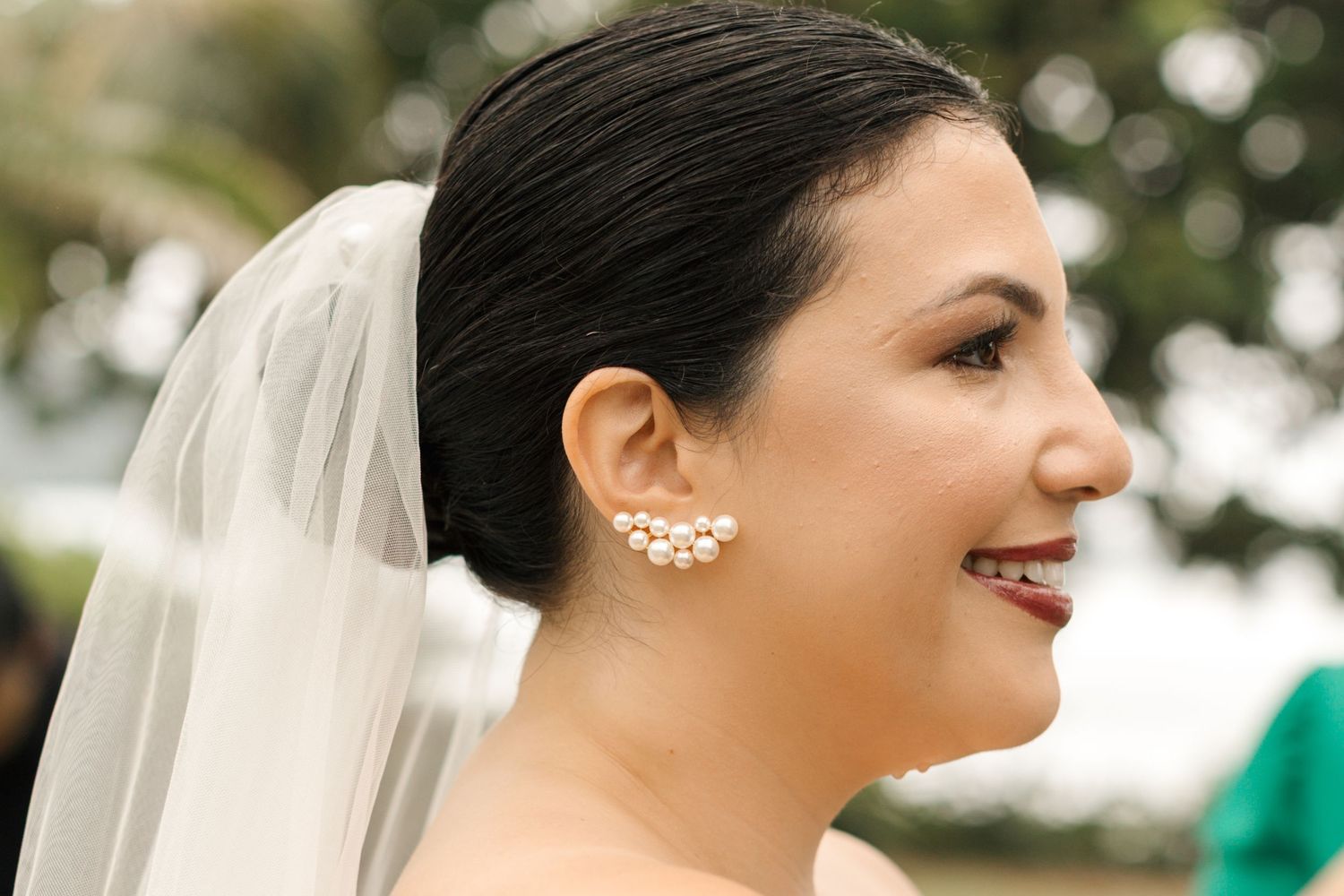 Closeup of bride's profile showing delicate pearl ear jewelry and veil.