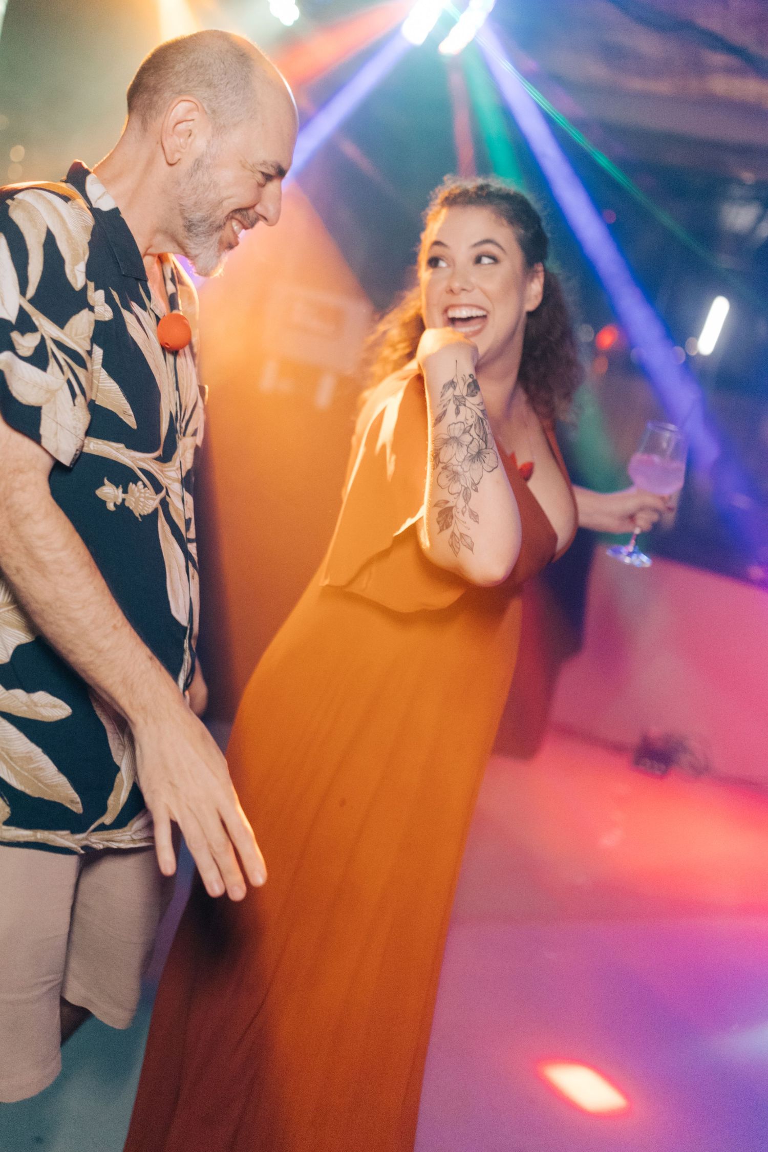 Wedding guests dance under vibrant multicolored party lights.