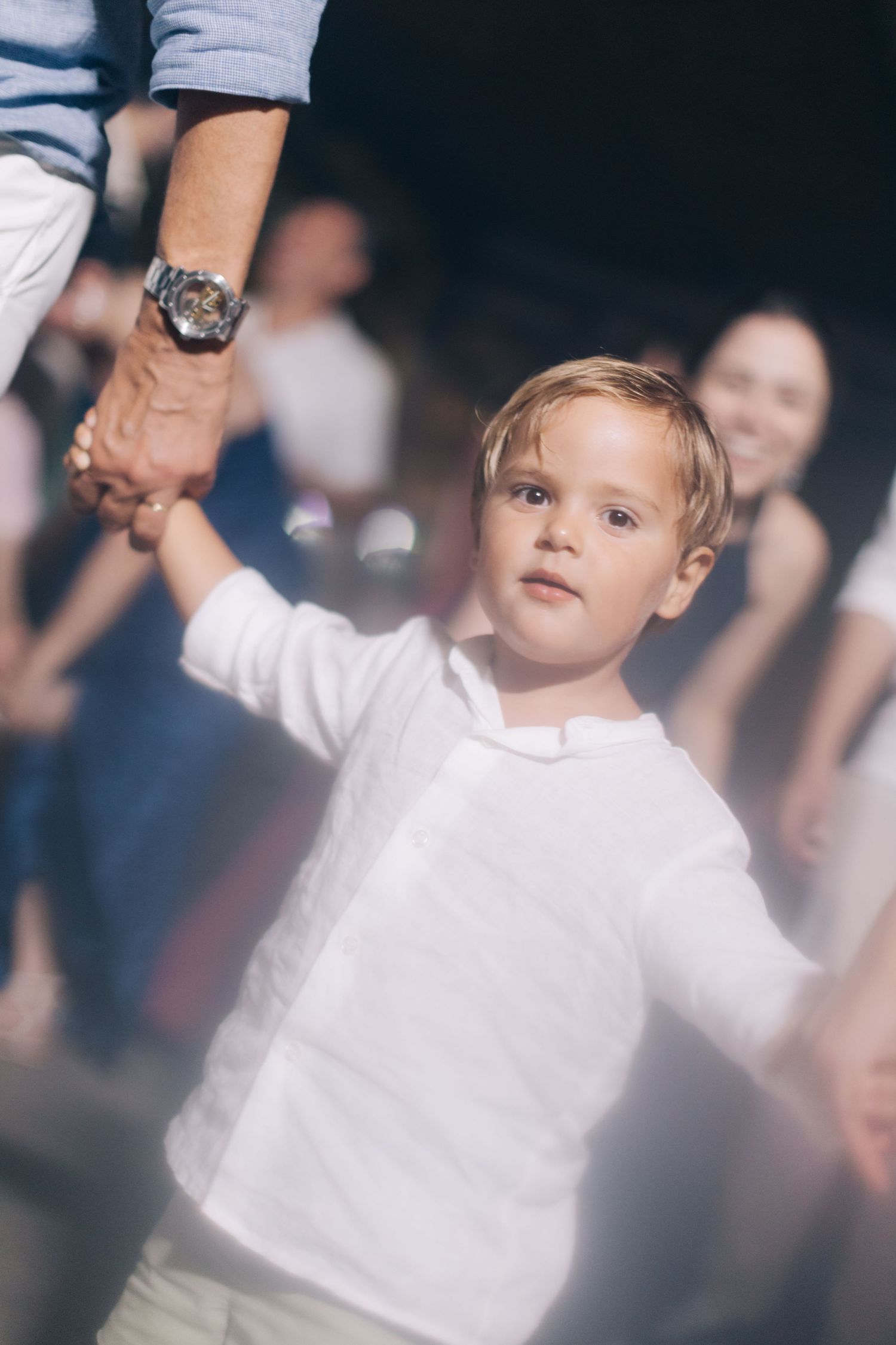 A young child dances while holding an adult's hand at a wedding reception.