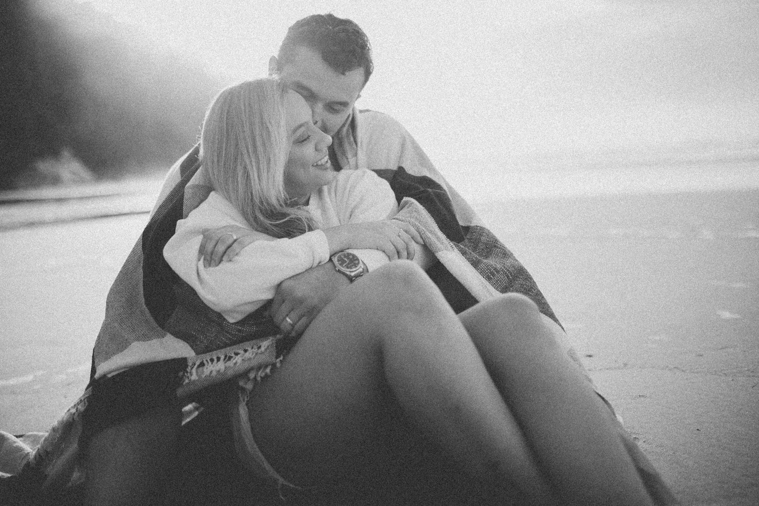 A couple shares a tender embrace while relaxing on the beach.