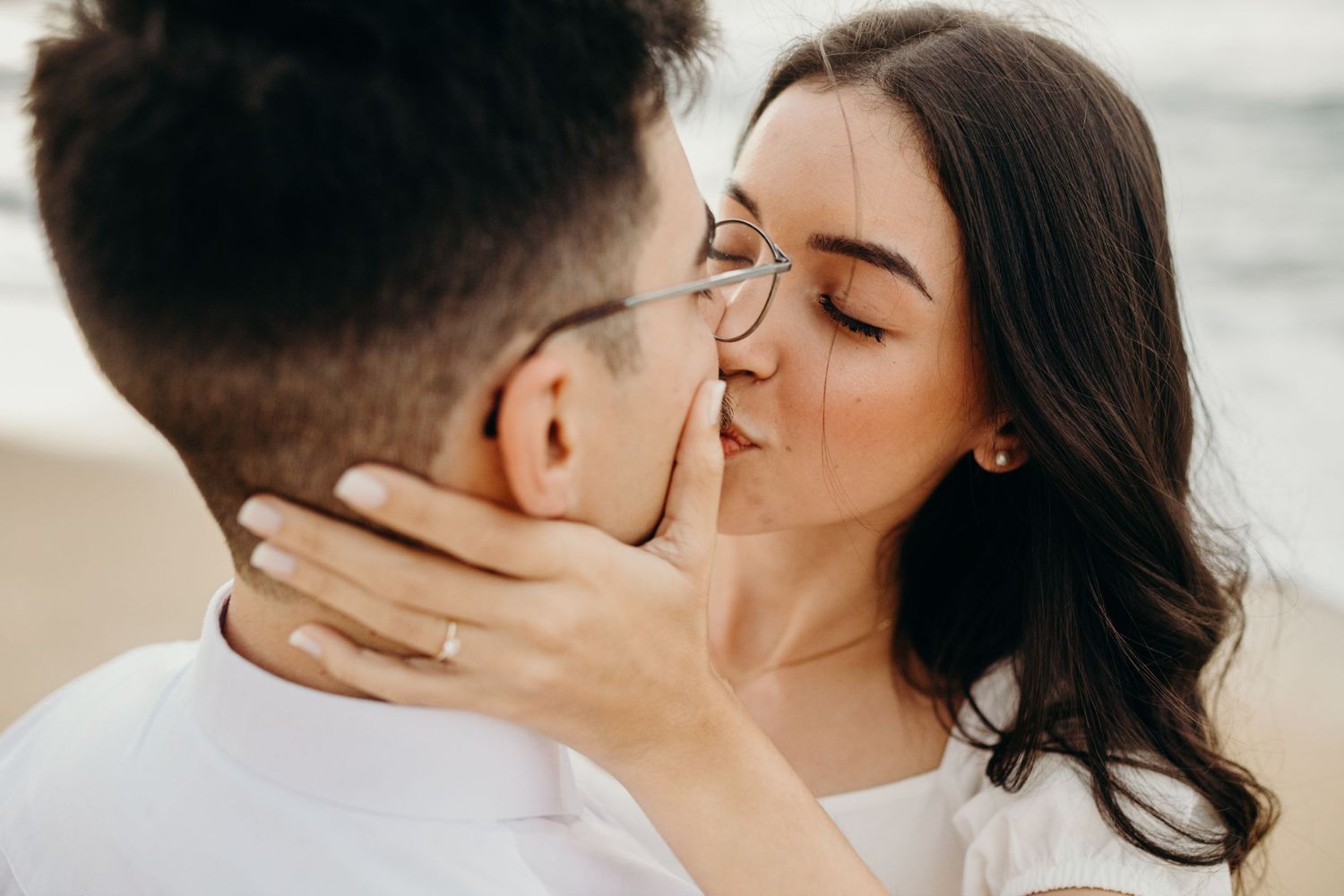 A close-up shot of a romantic kiss between a couple in white outfits.