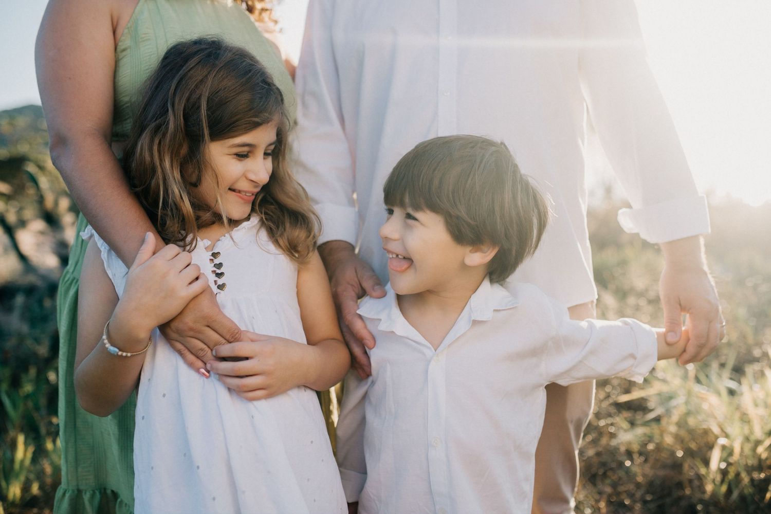 Two children laugh and interact while standing together outdoors.