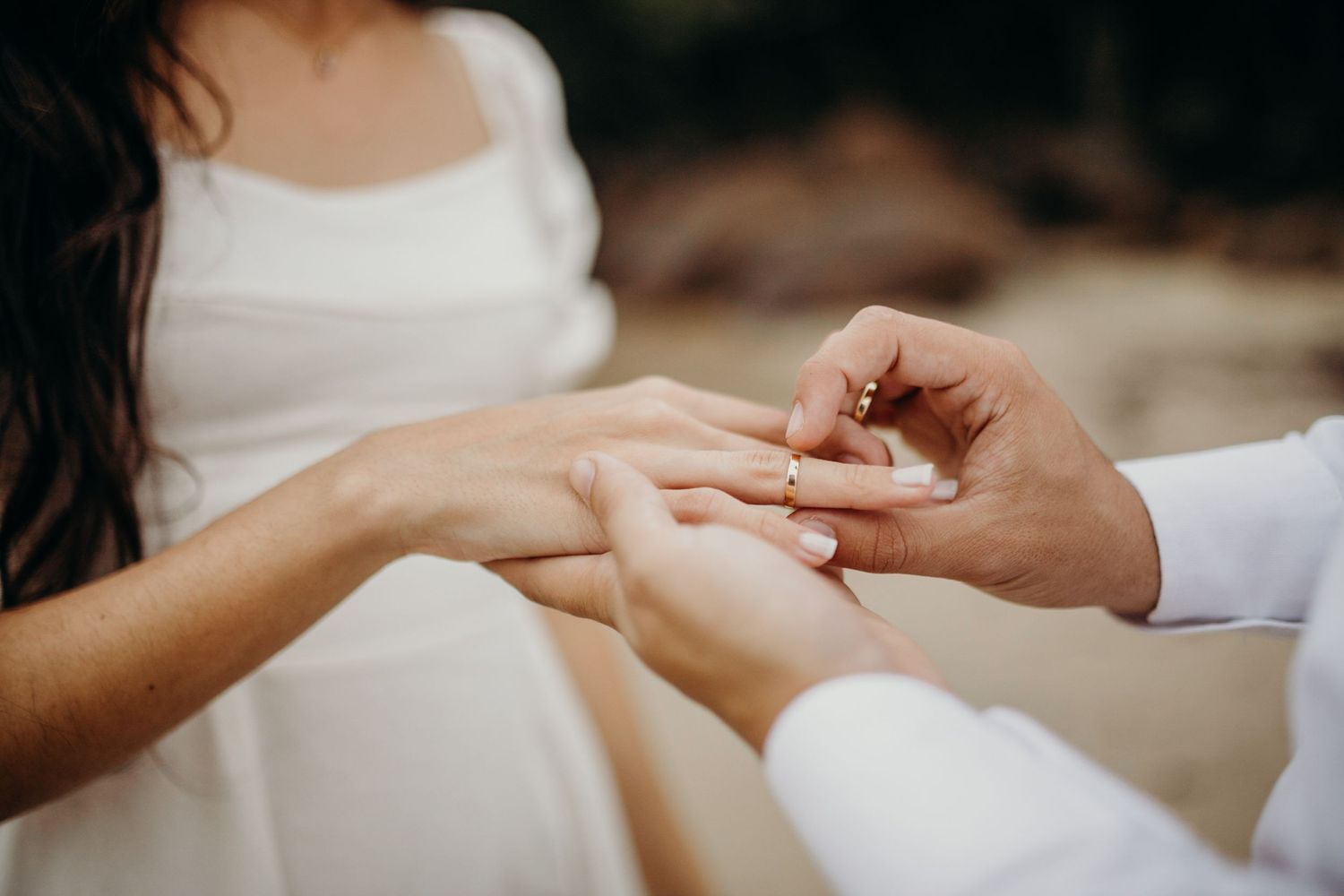 Detail shot of hands during beachside proposal with ring.