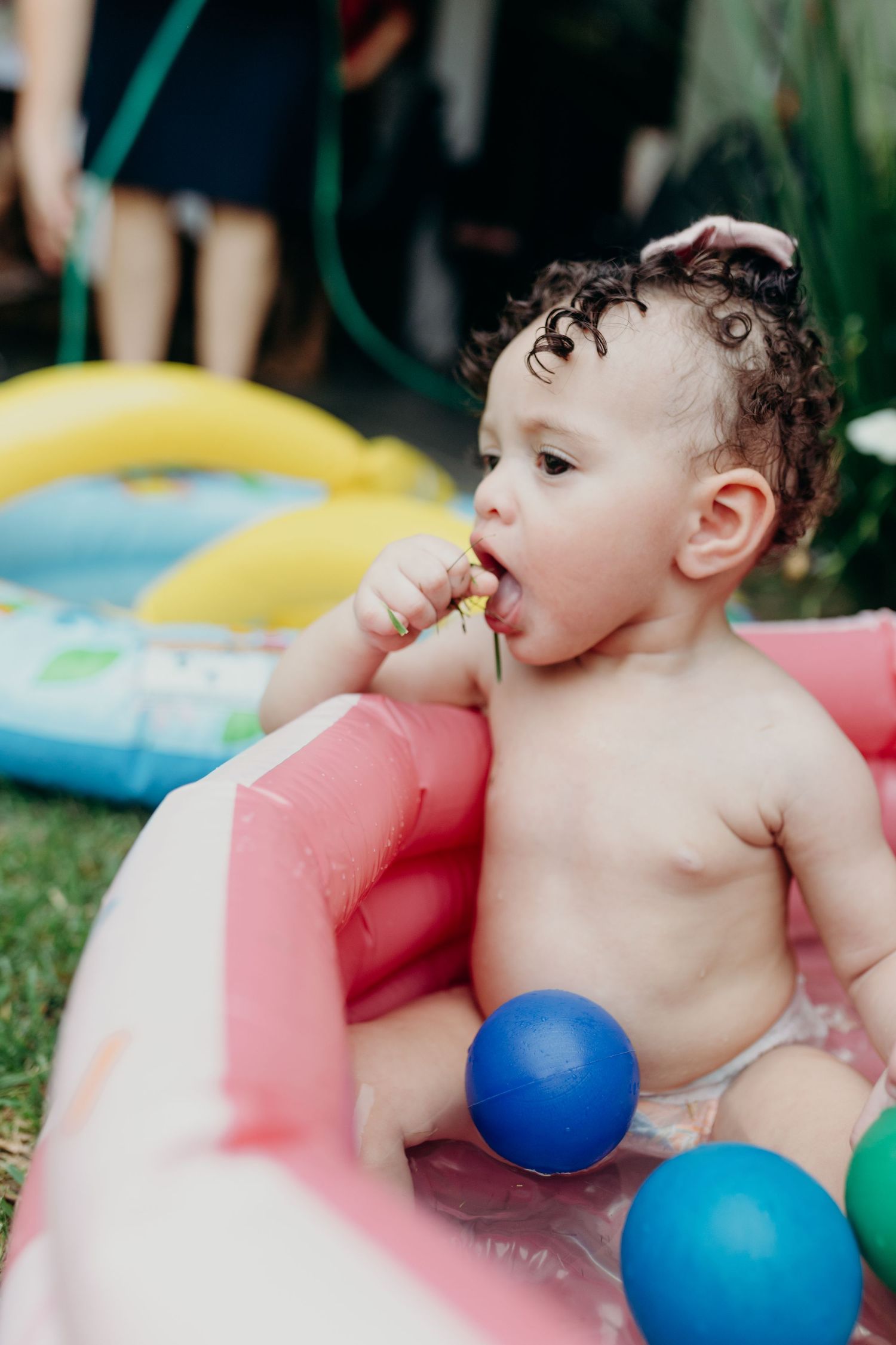 Colorful inflatable pool filled with play balls on grass during summer.