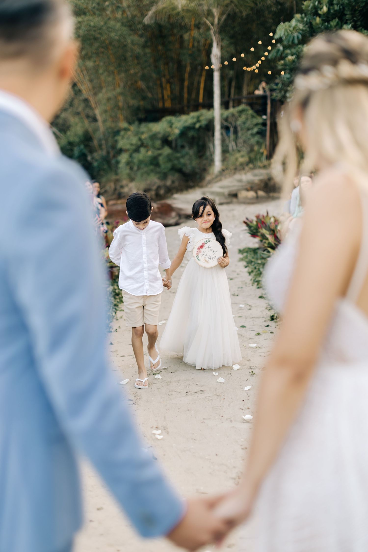 Garden wedding ceremony with string lights and guests watching.