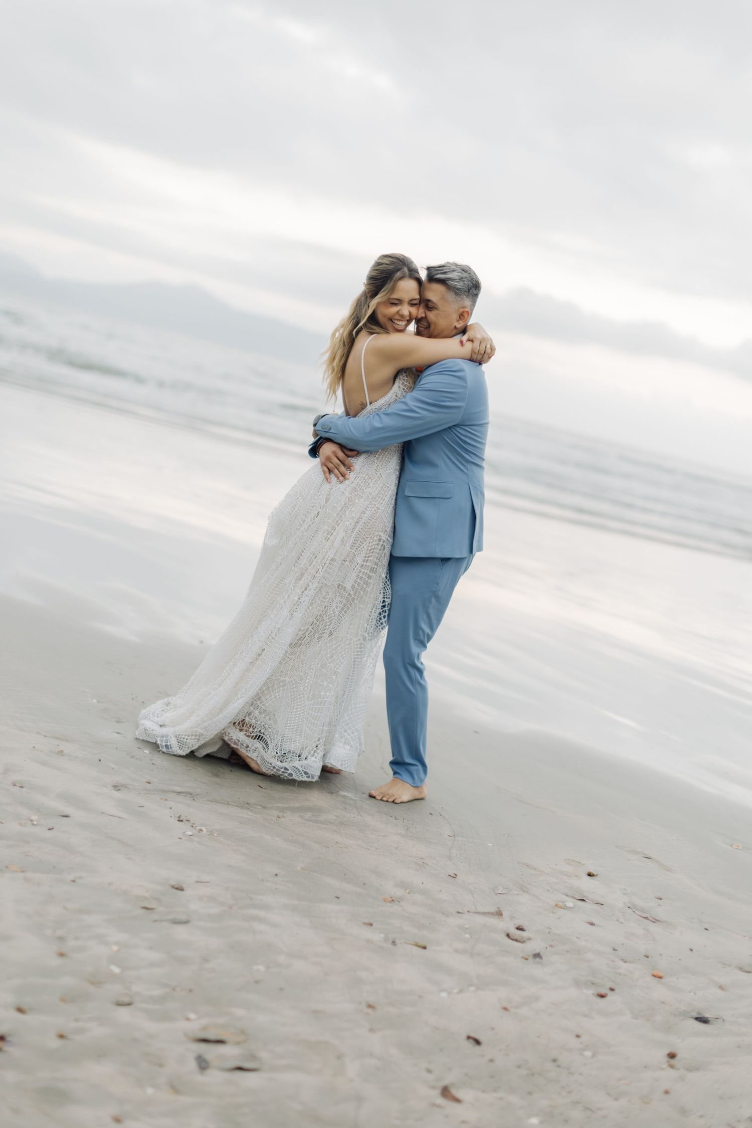 Intimate beach wedding photos with couple embracing on the shoreline.