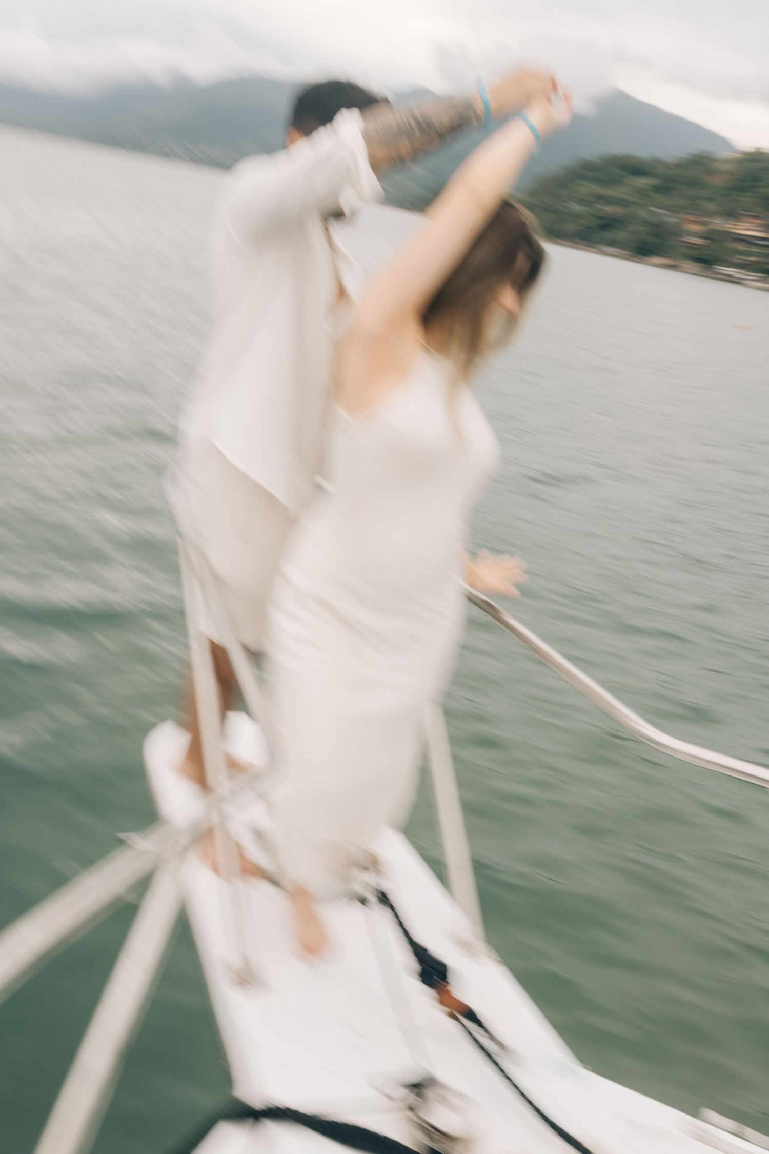 Dancing pair in white outfits share a blurred motion moment on a boat deck.
