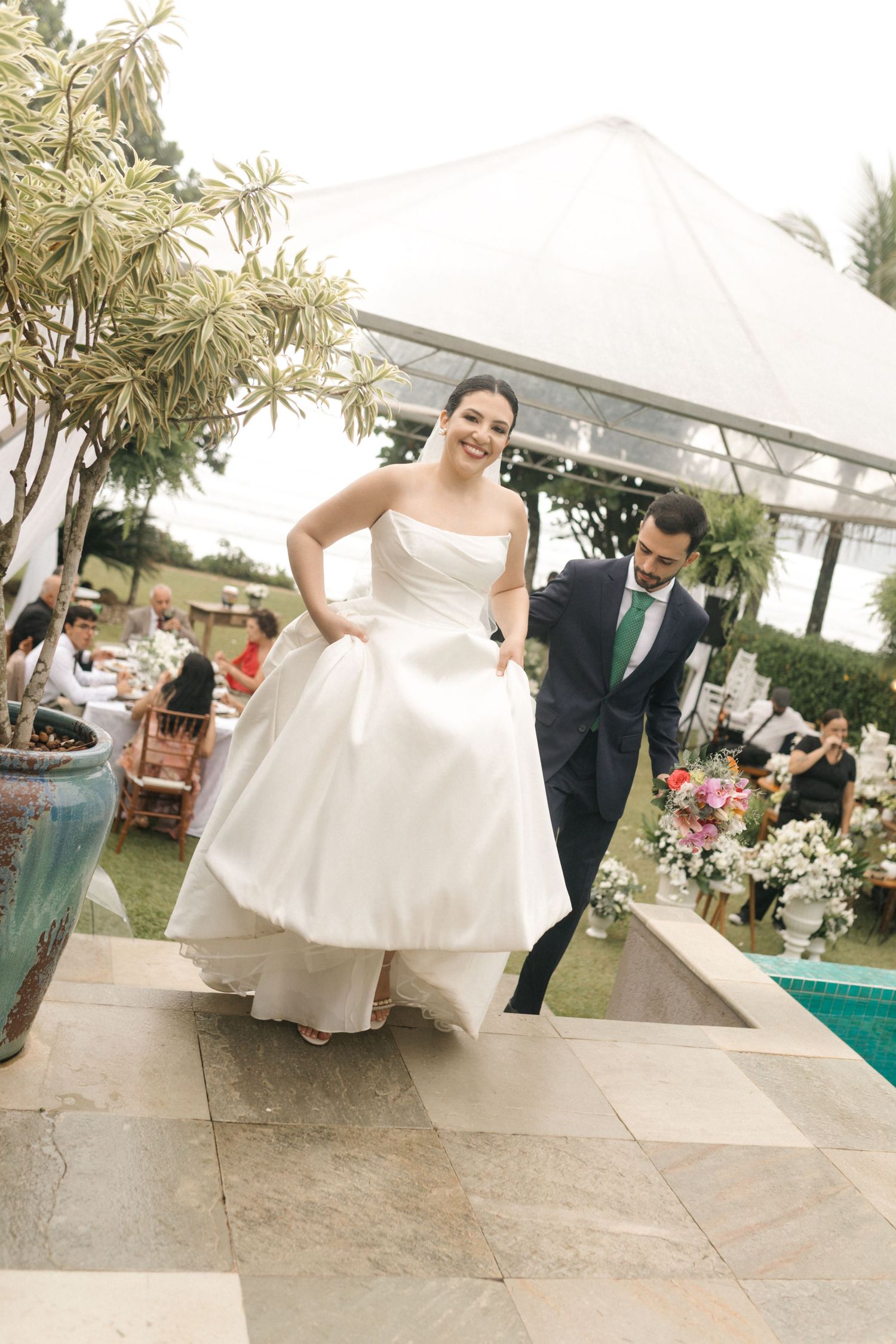 A bride in white dress walking across a stone patio at an outdoor venue.