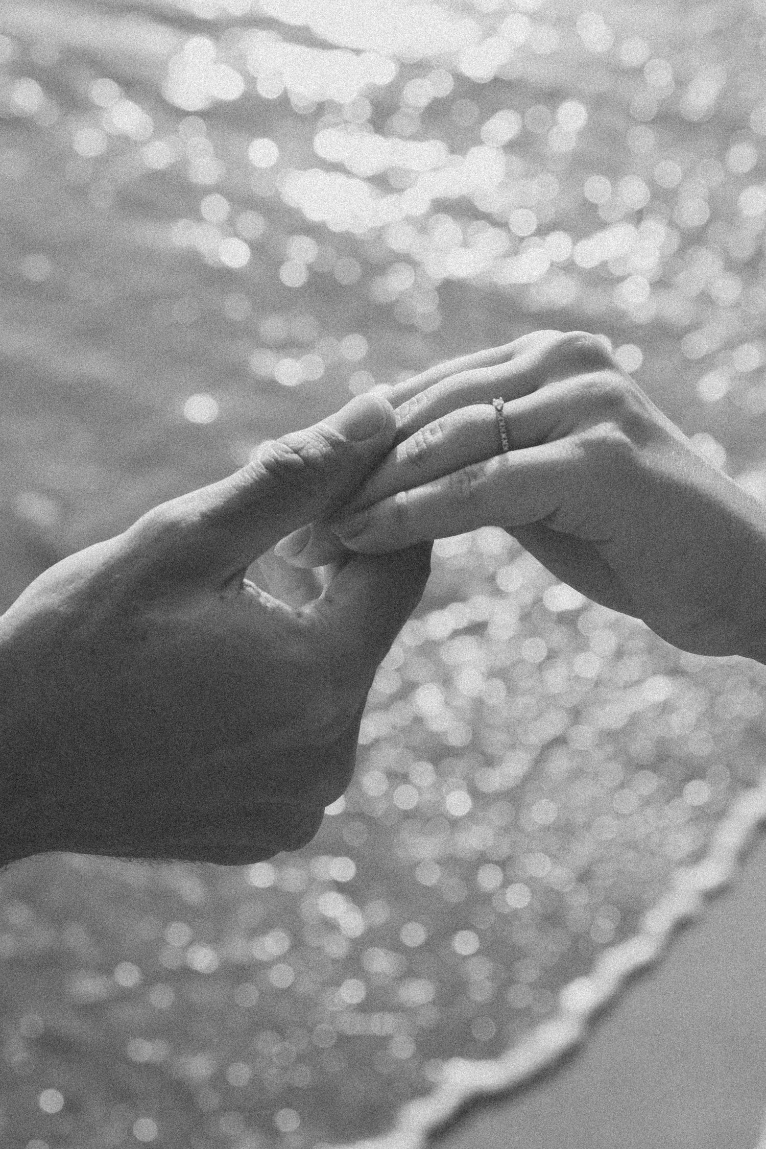 Close-up of hands touching with sparkling bokeh water in the background.
