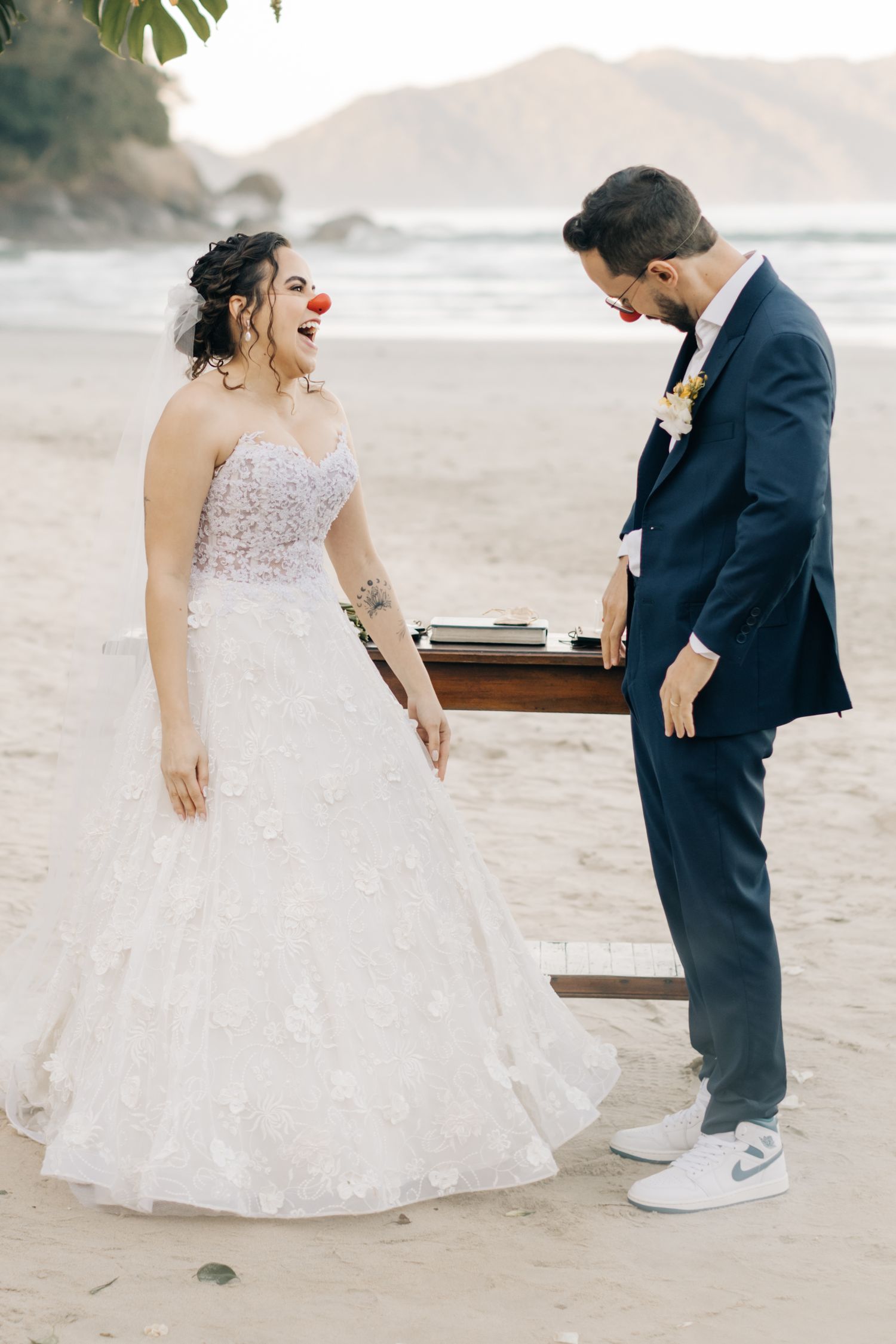 Candid laughing moment between couple during beach wedding ceremony.