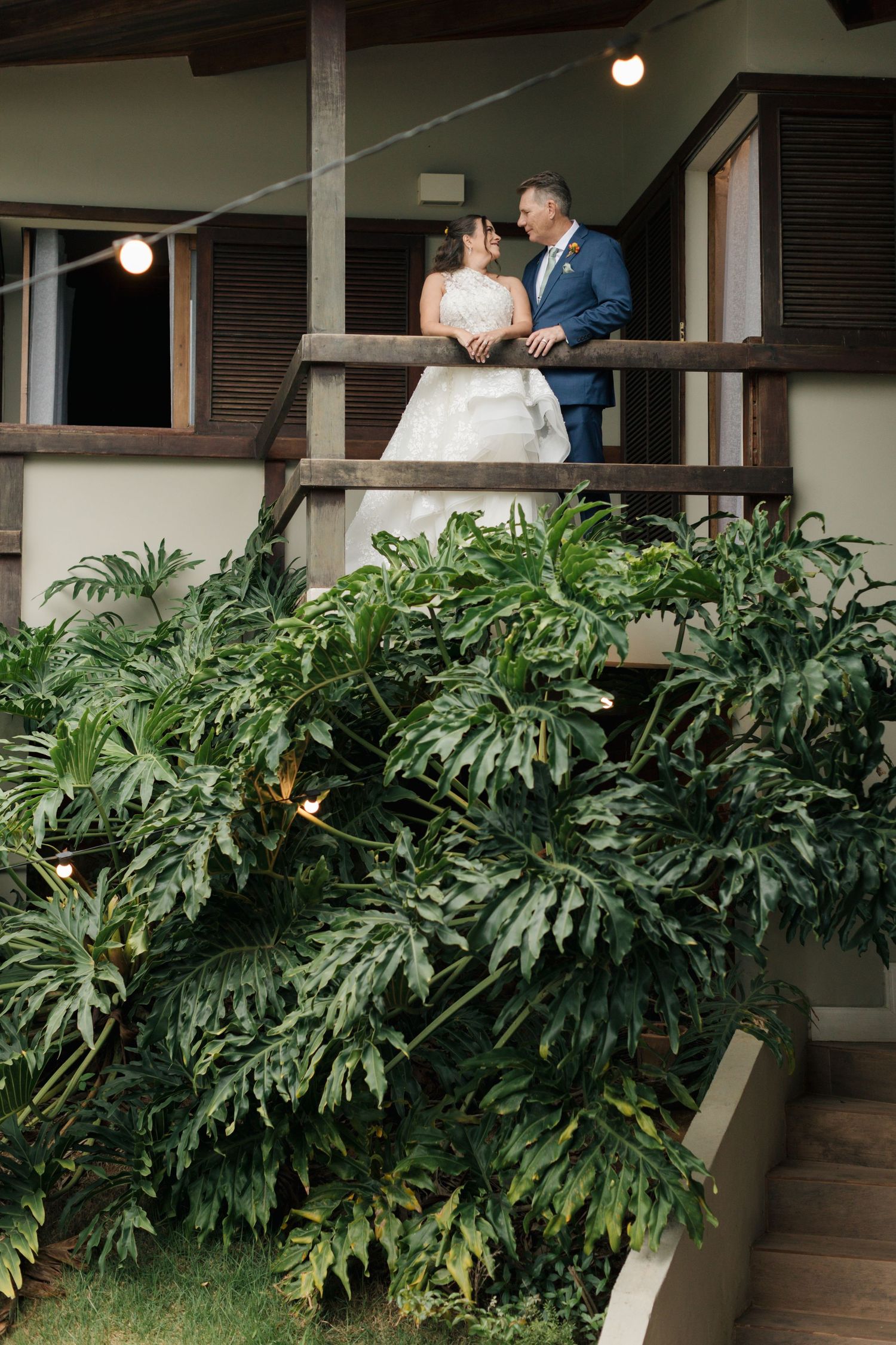 Tropical plants and monstera leaves frame a covered outdoor patio area.