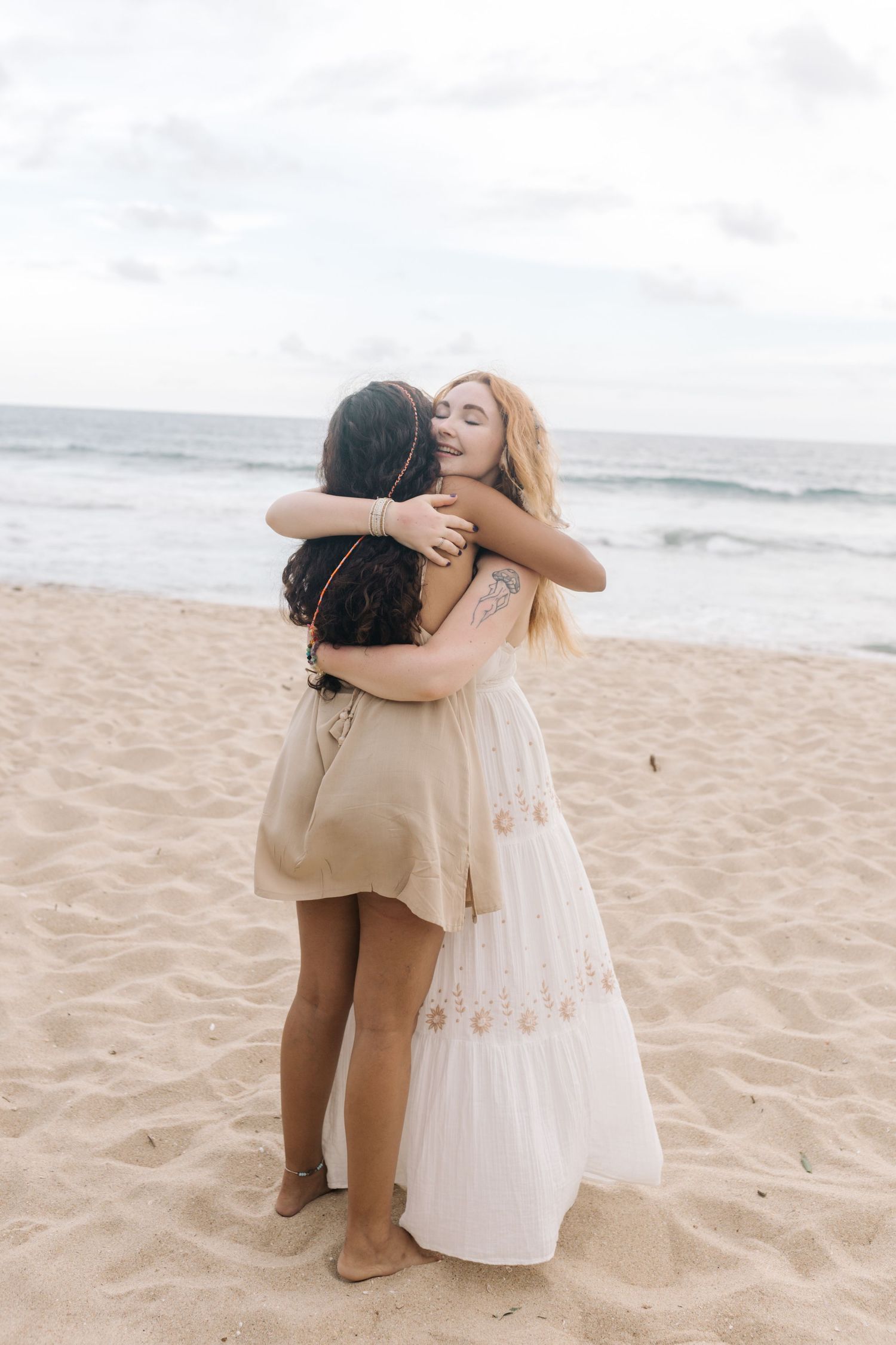 Two people share an emotional embrace on a sandy beach.