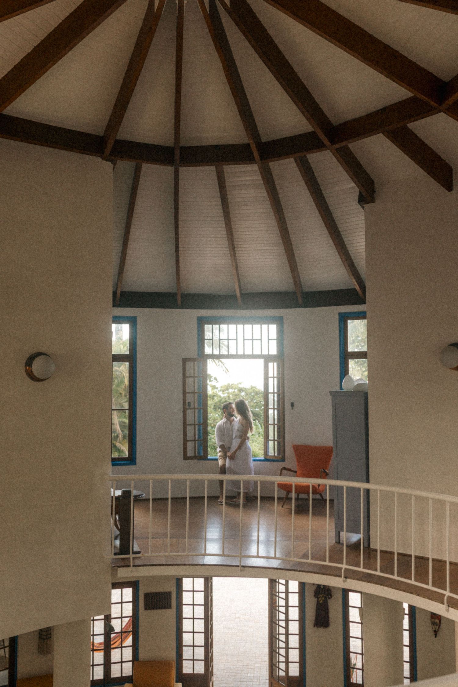 Interior view of a circular room with vaulted ceiling and wooden beams showing a couple on an upper balcony.