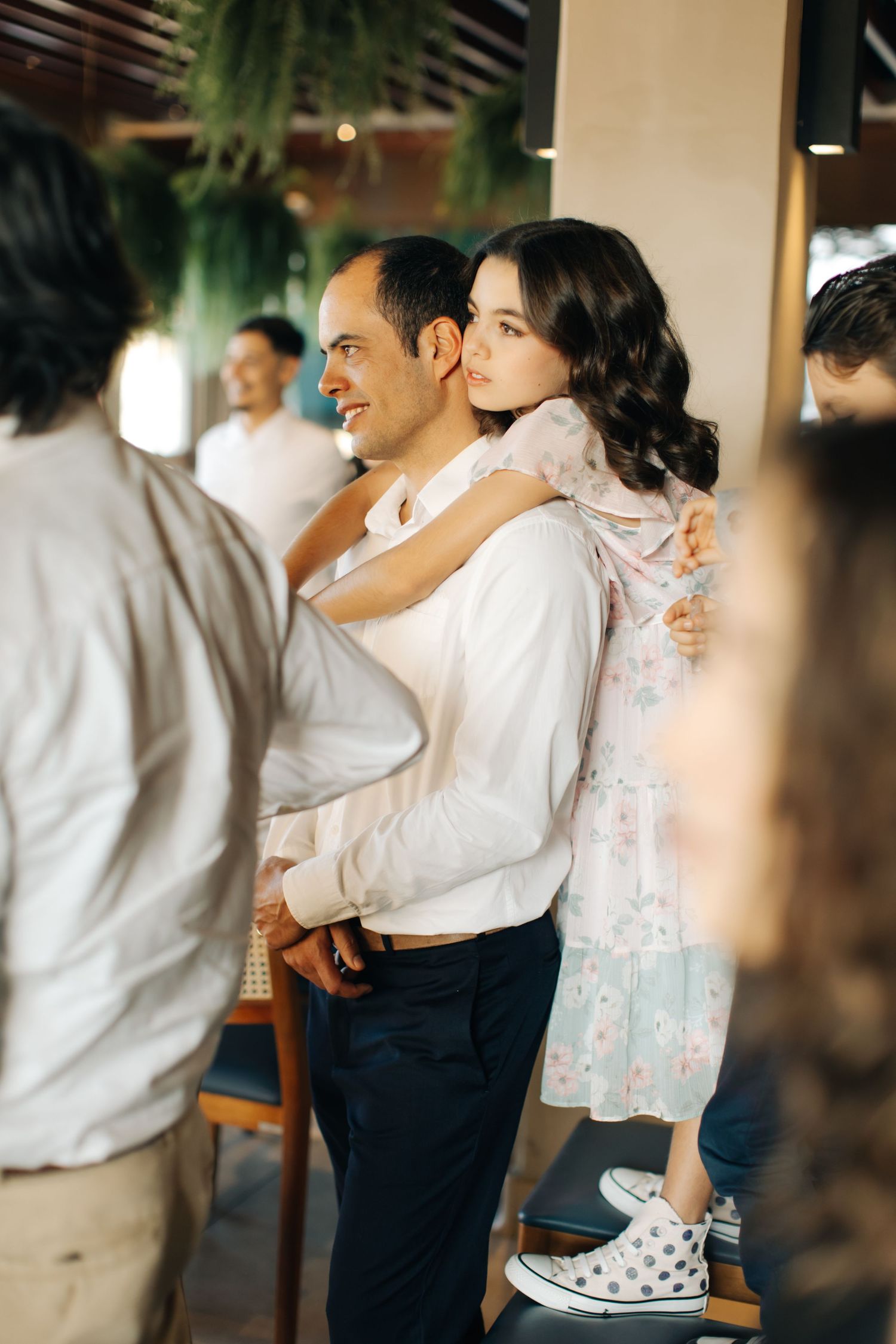 A young girl in a floral dress being lifted up during wedding celebrations.