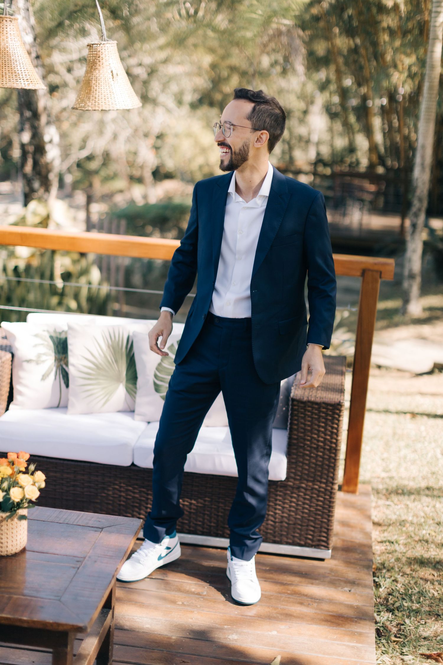 Candid shot of groom in navy suit and sneakers on outdoor patio.