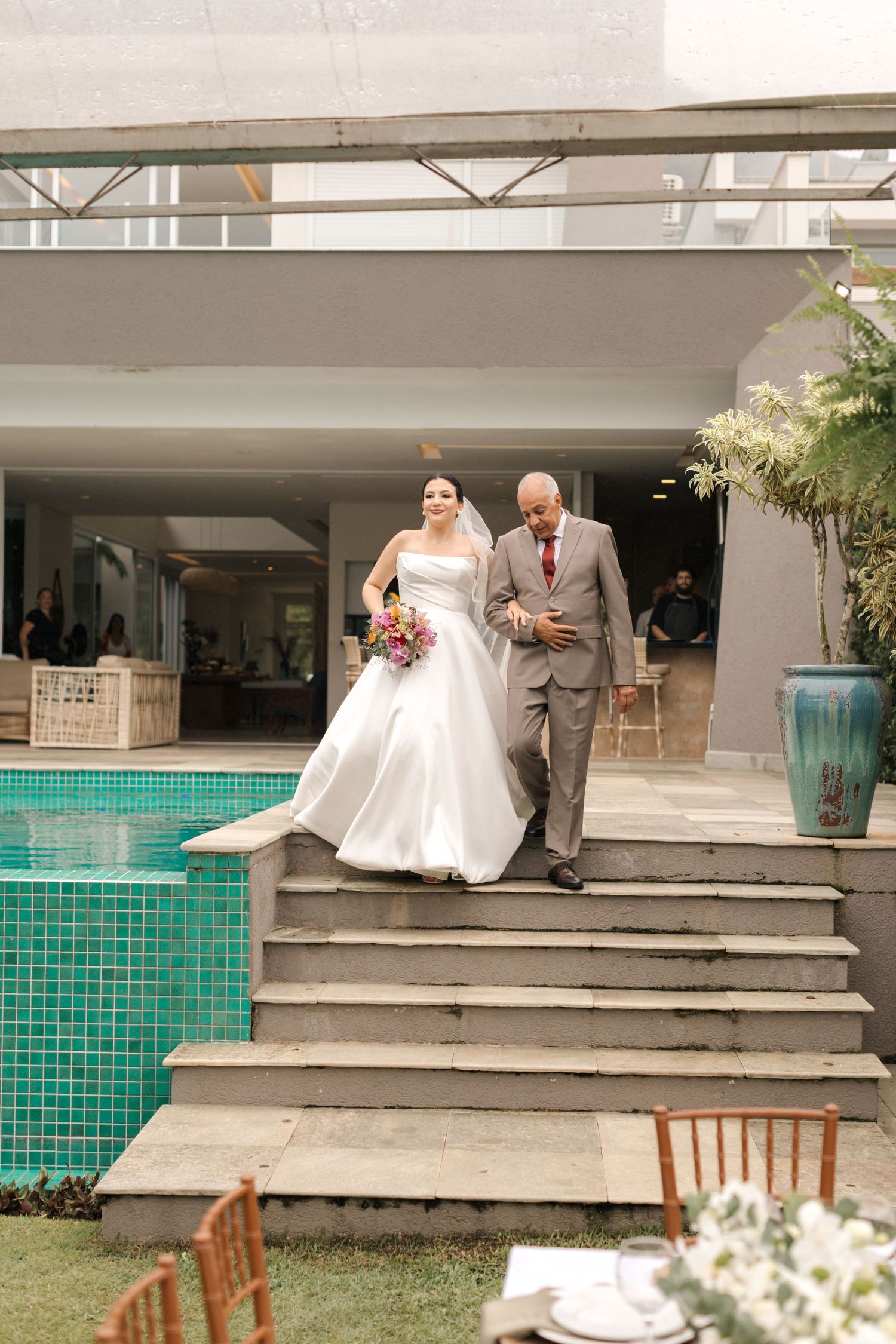 Wedding party descending concrete steps at modern venue with turquoise tile details.