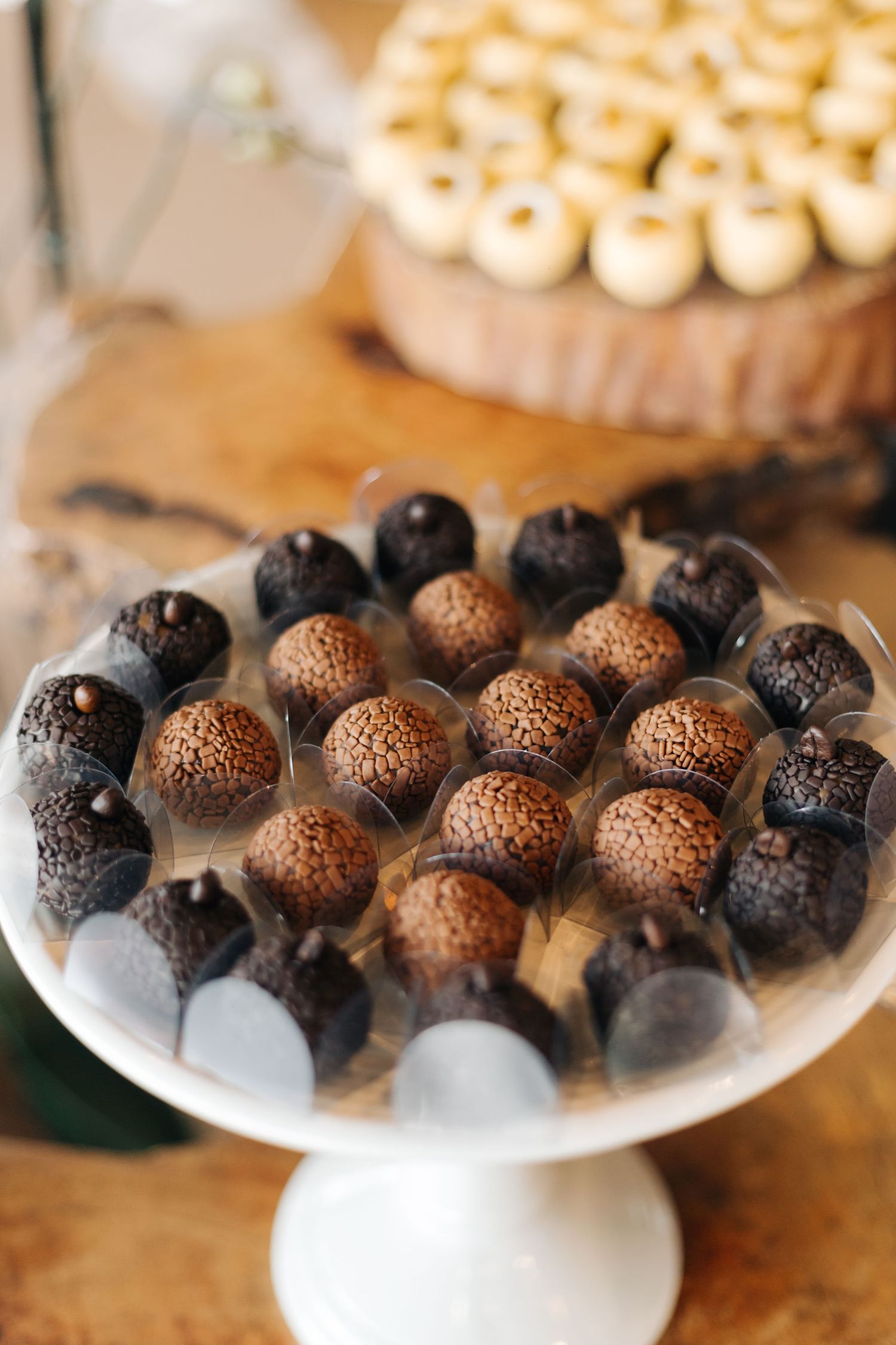 Chocolate truffles in brown and black varieties displayed on a white cake stand.