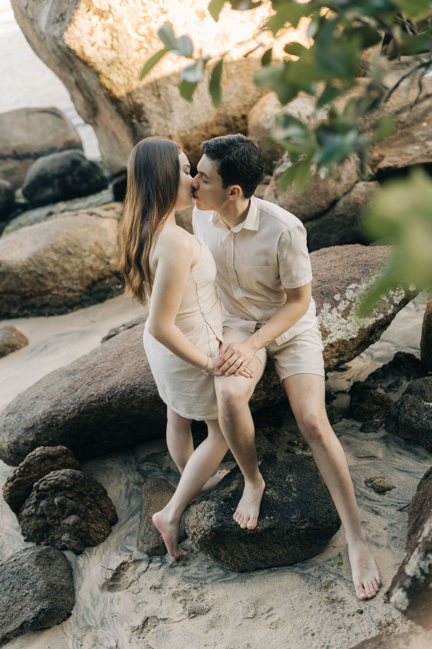 Couple sharing intimate moment on rocky beach formation.