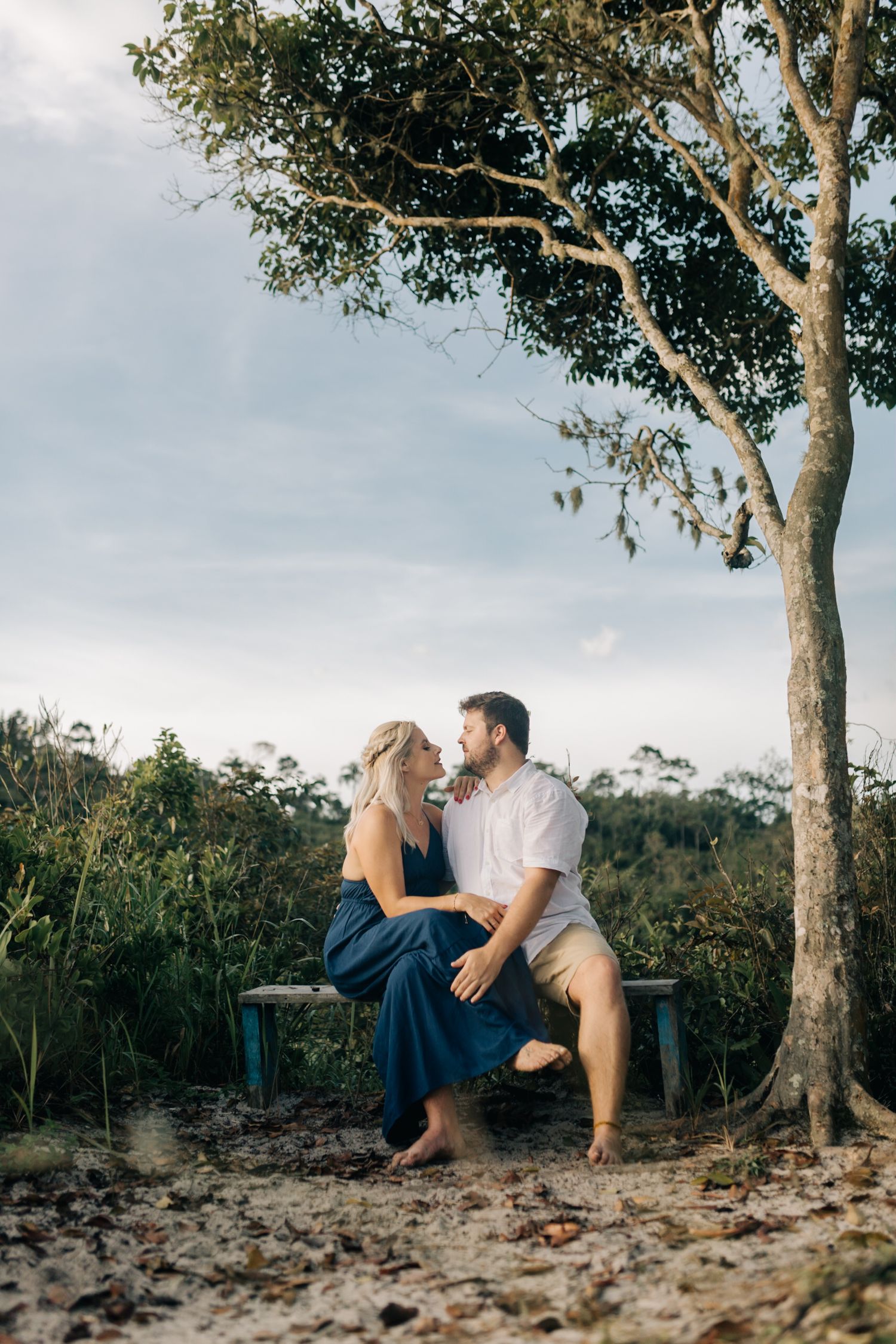 Romantic couple sitting under large eucalyptus trees in natural outdoor setting.