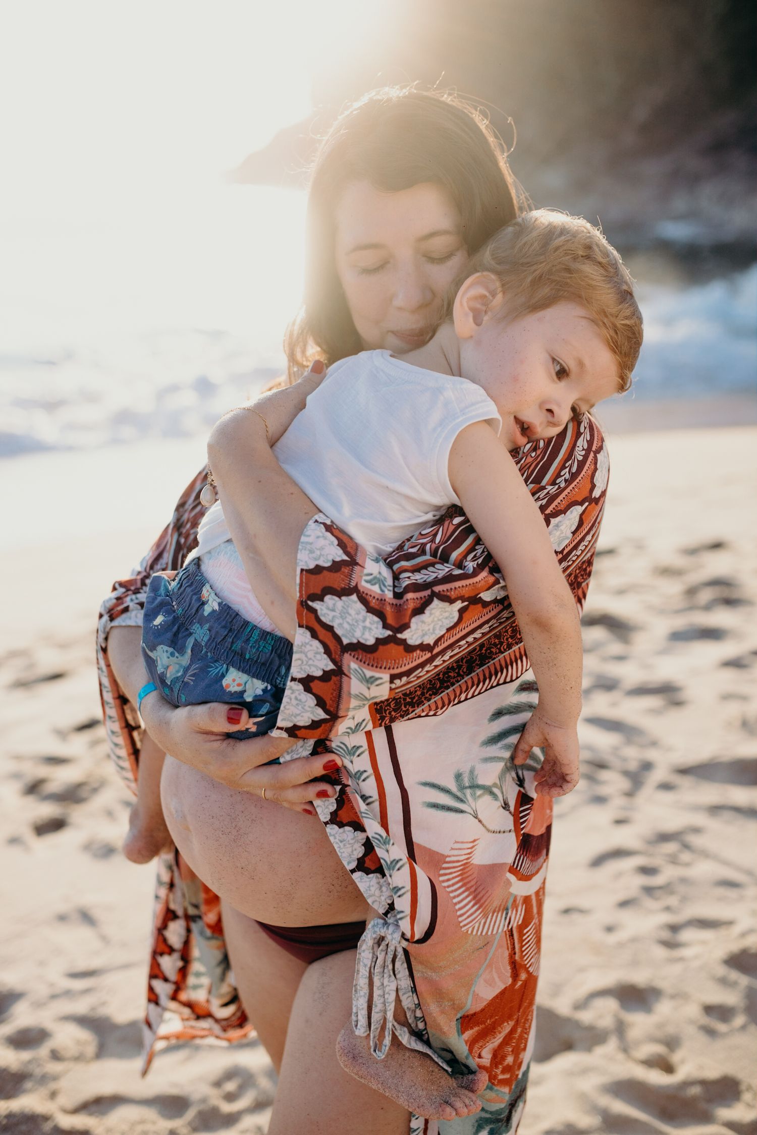 Intimate beach portrait with vibrant patterned fabric during golden hour.