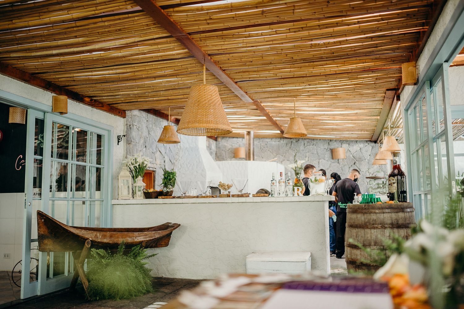 Rustic bar area with wooden ceiling beams and pendant lighting in tropical resort setting.