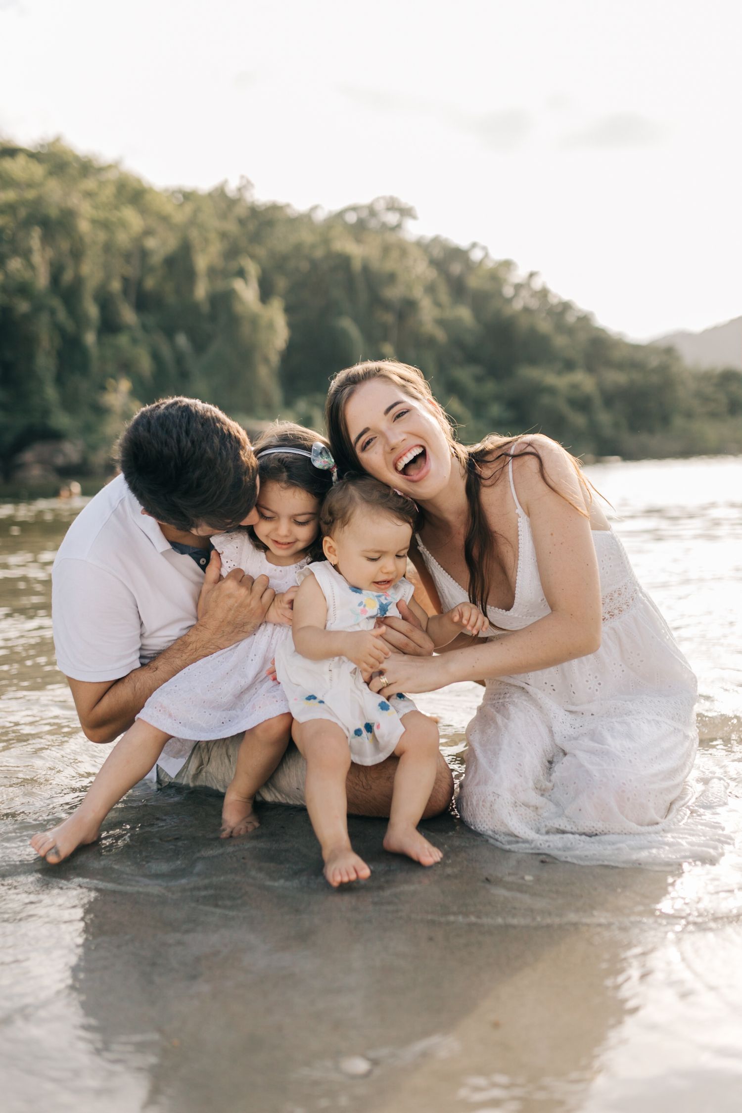 Joyful family moment playing together at the beach shore during golden hour.
