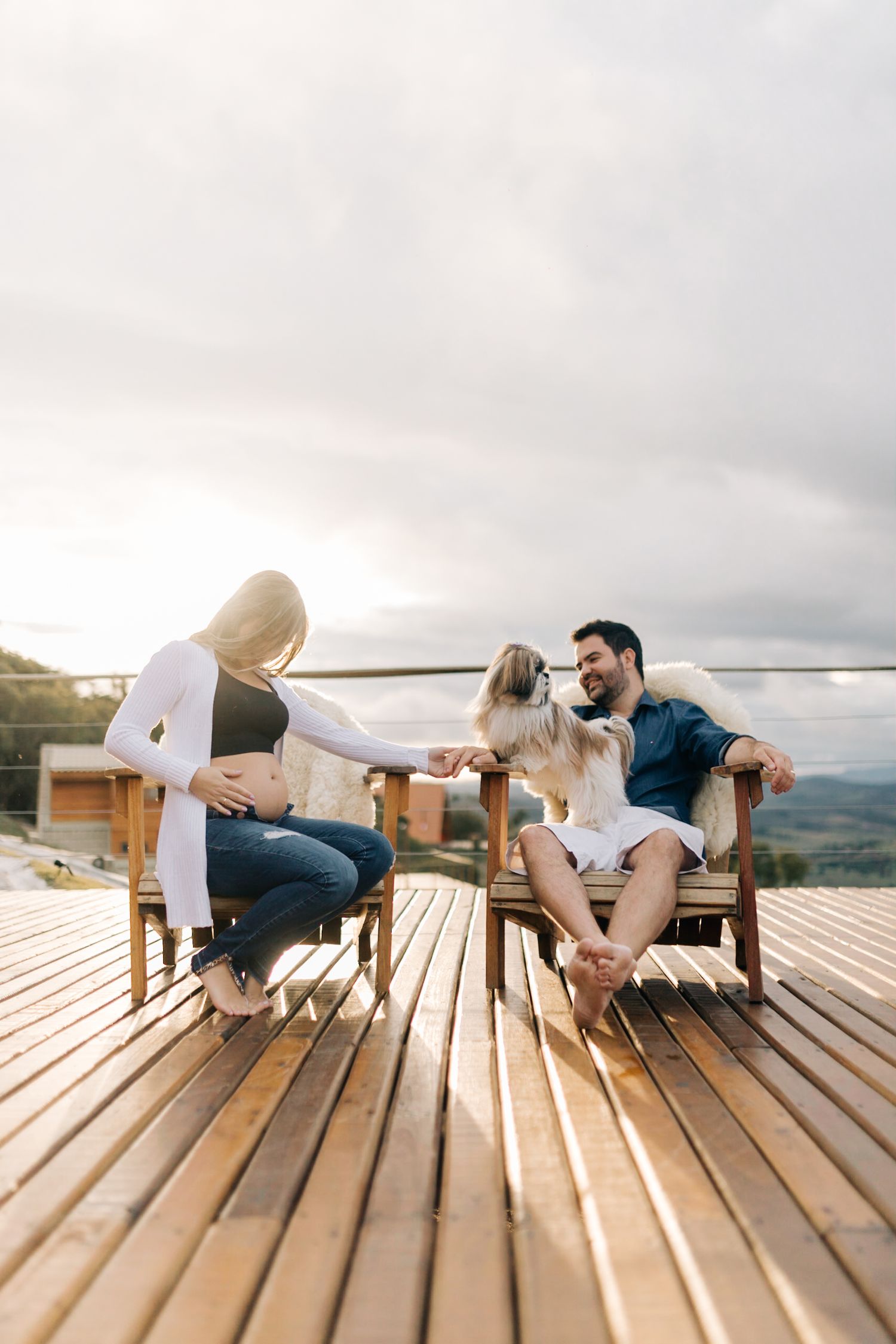 A couple relaxes on a wooden deck with scenic mountain views at sunset.