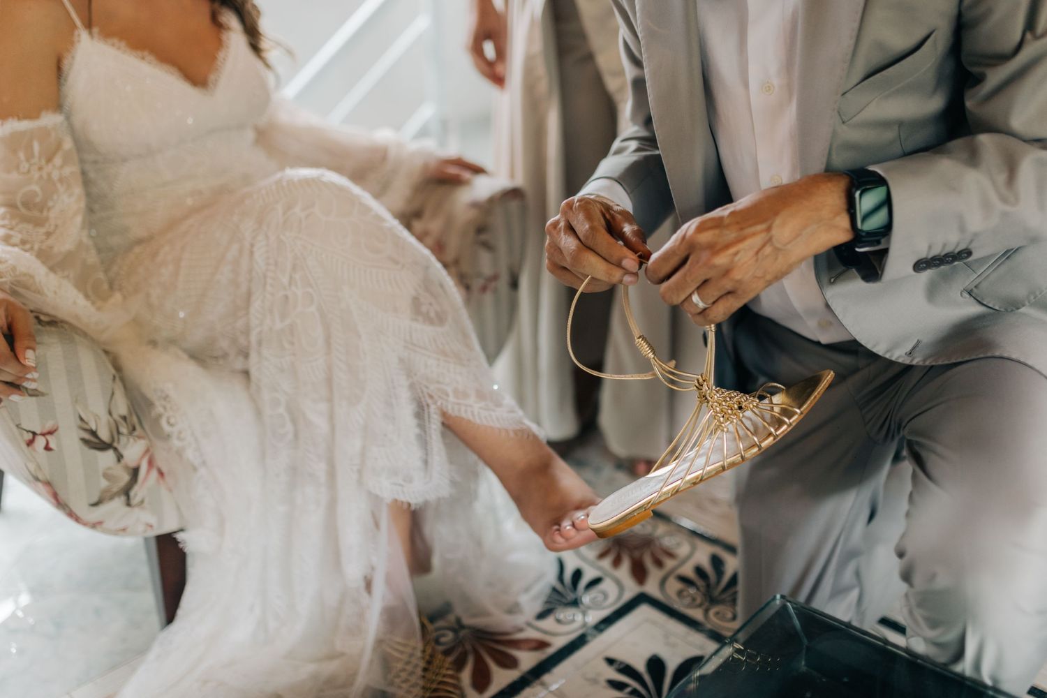 Close up of wedding dress and shoes on patterned tile floor.