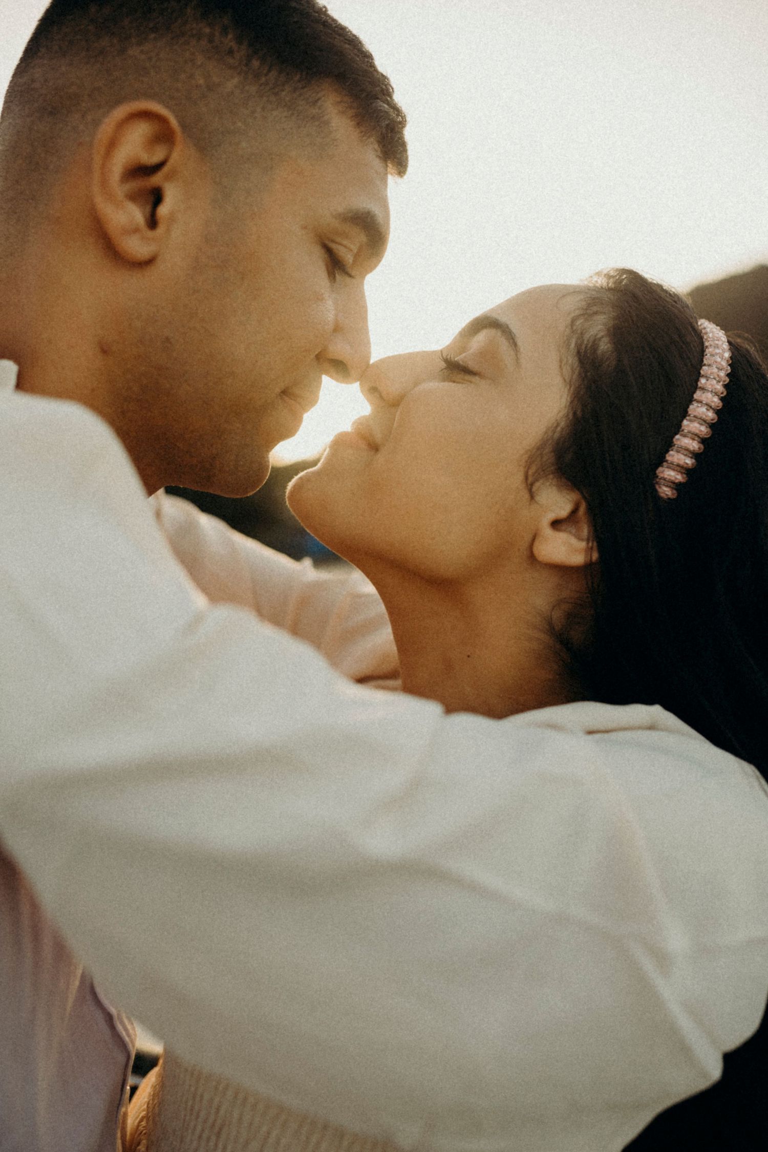 An intimate close-up of a couple in white clothing sharing a tender moment.