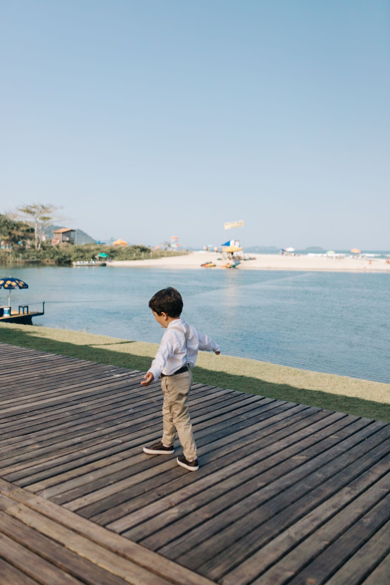 Child playing on wooden deck overlooking scenic beach and ocean view.