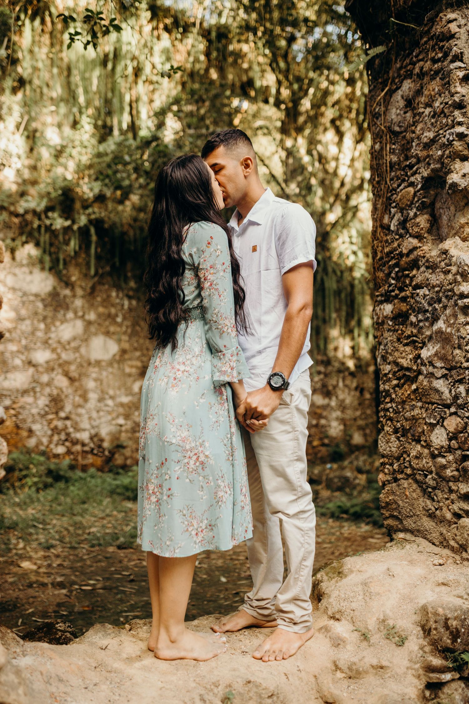 A tender moment shared between a couple against weathered stone walls and moss.