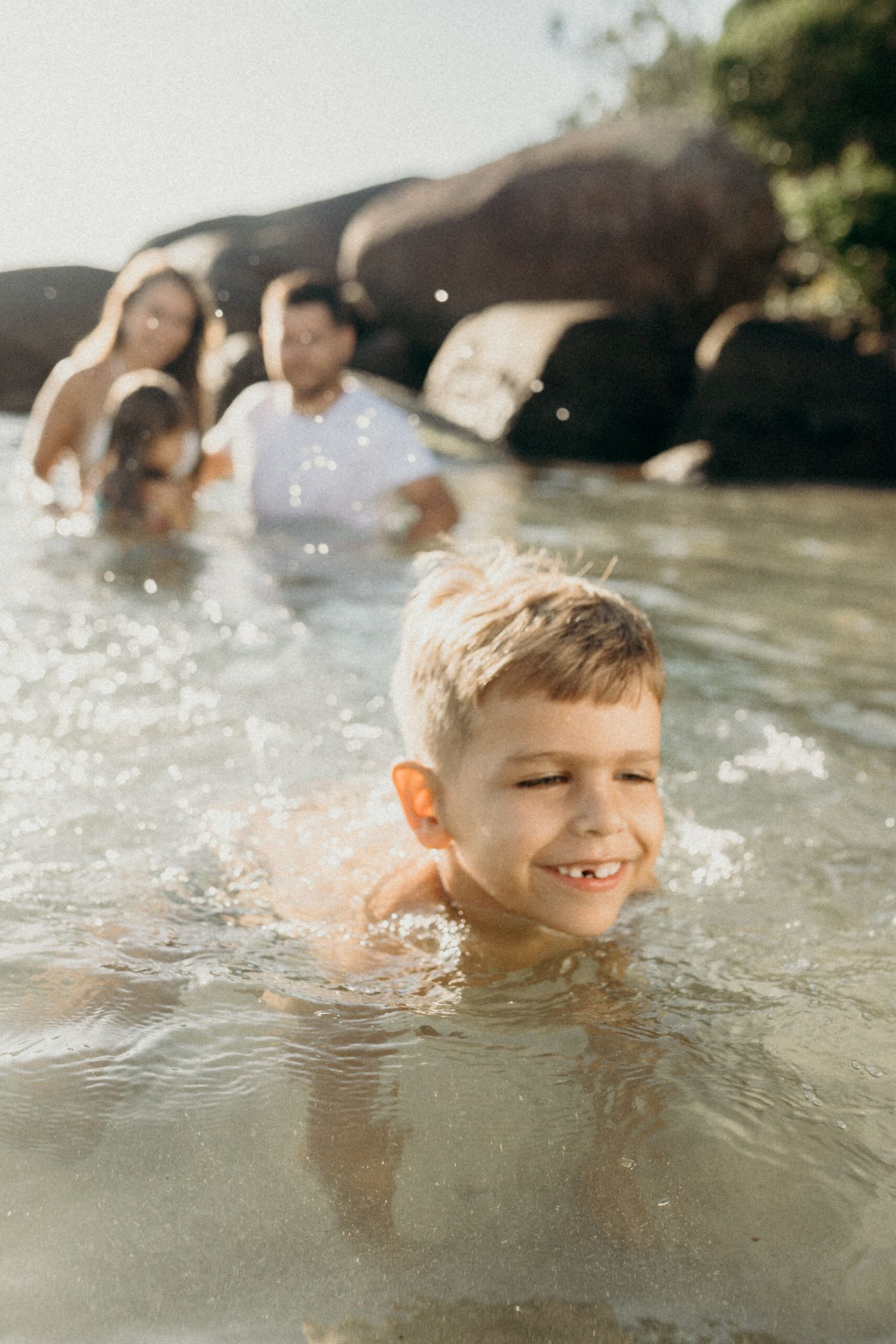 Child swimming and playing in clear ocean water during a sunny day.