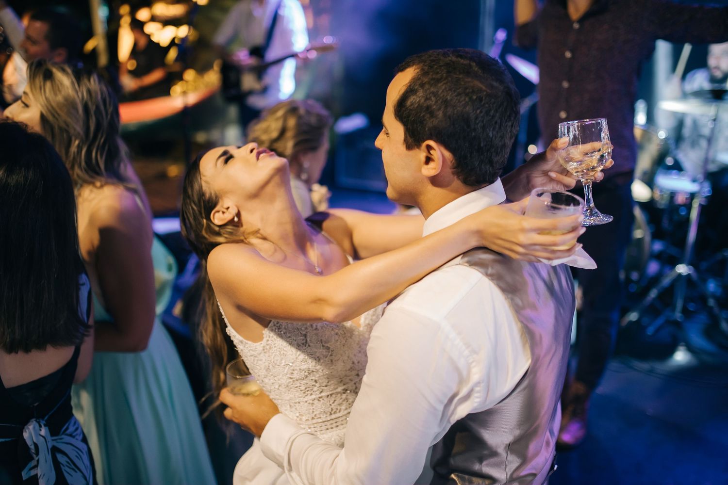 Couples dancing and embracing on the dance floor at a wedding reception with blue lighting.