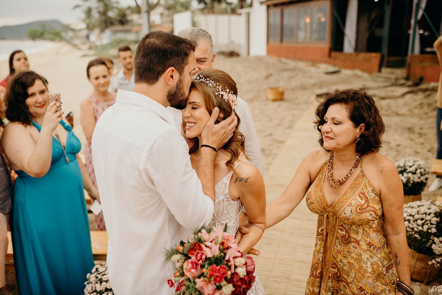 Wedding guests in turquoise and coral dresses celebrating at a beach reception.