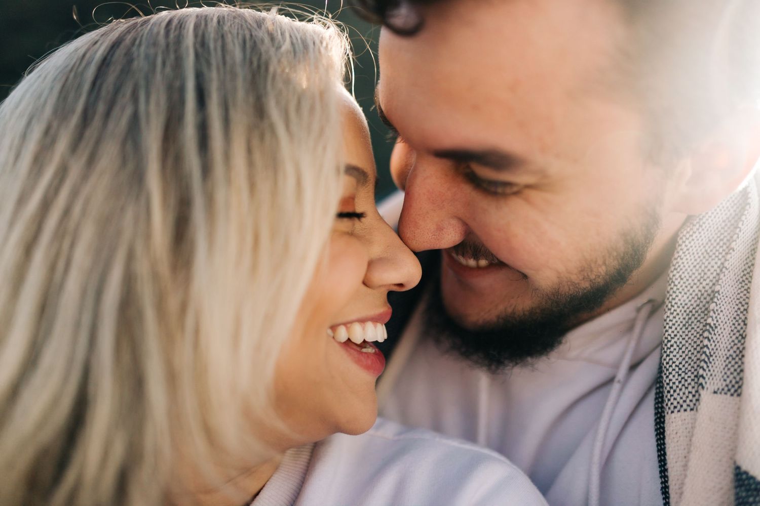 Close up romantic portrait of a couple sharing an intimate moment in soft lighting.