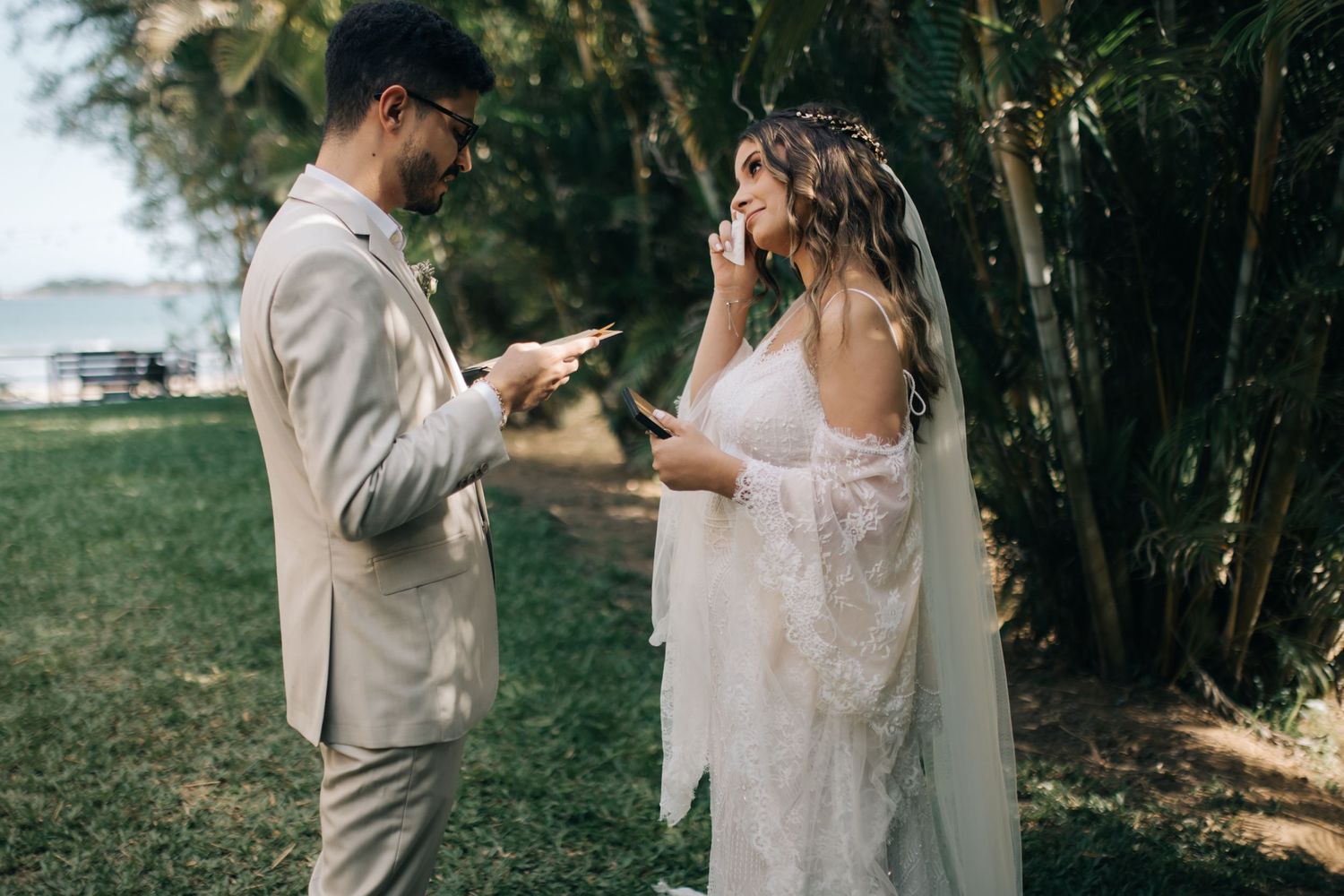 A couple shares their first look during an intimate outdoor wedding ceremony under lush trees.