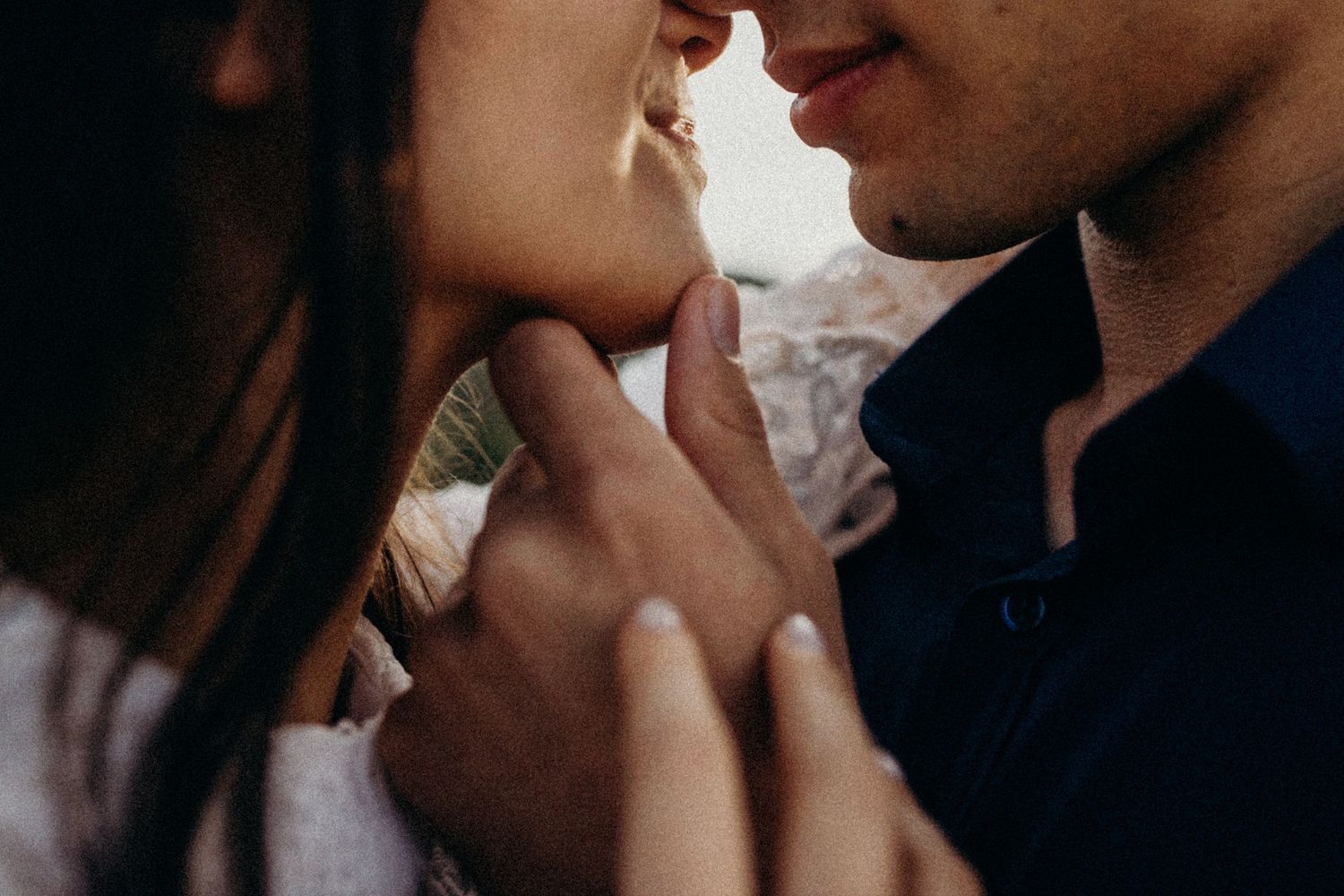 An intimate engagement photoshoot moment captured in warm natural lighting against a neutral background.
