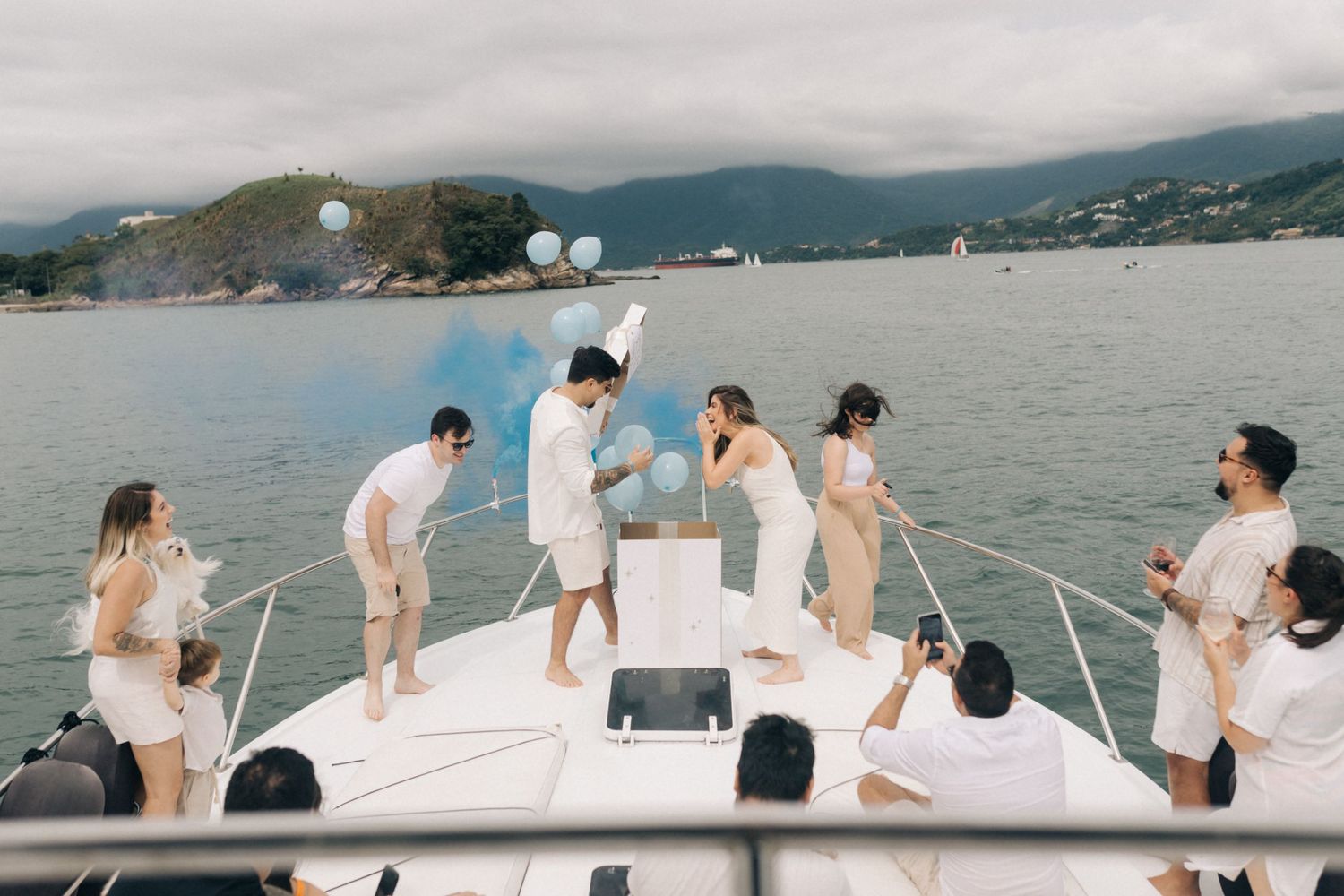 White yacht cruise with passengers relaxing against scenic mountain backdrop.