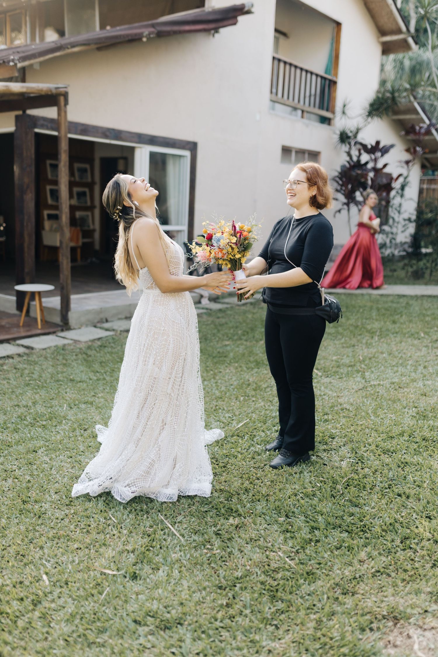 Two people share a candid moment exchanging a vibrant floral bouquet in an outdoor garden setting.
