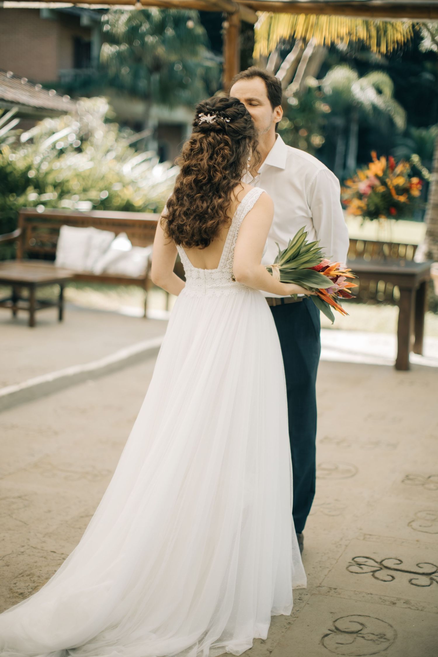 A couple shares an intimate moment during their first dance at an outdoor reception.