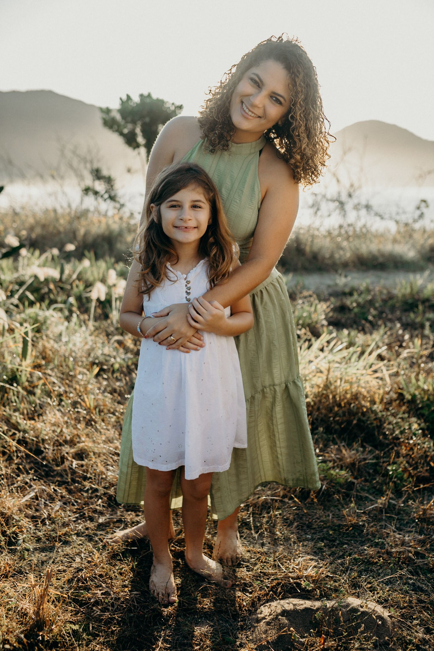Sweet outdoor portrait showing an embrace between two people in a natural setting with mountains.