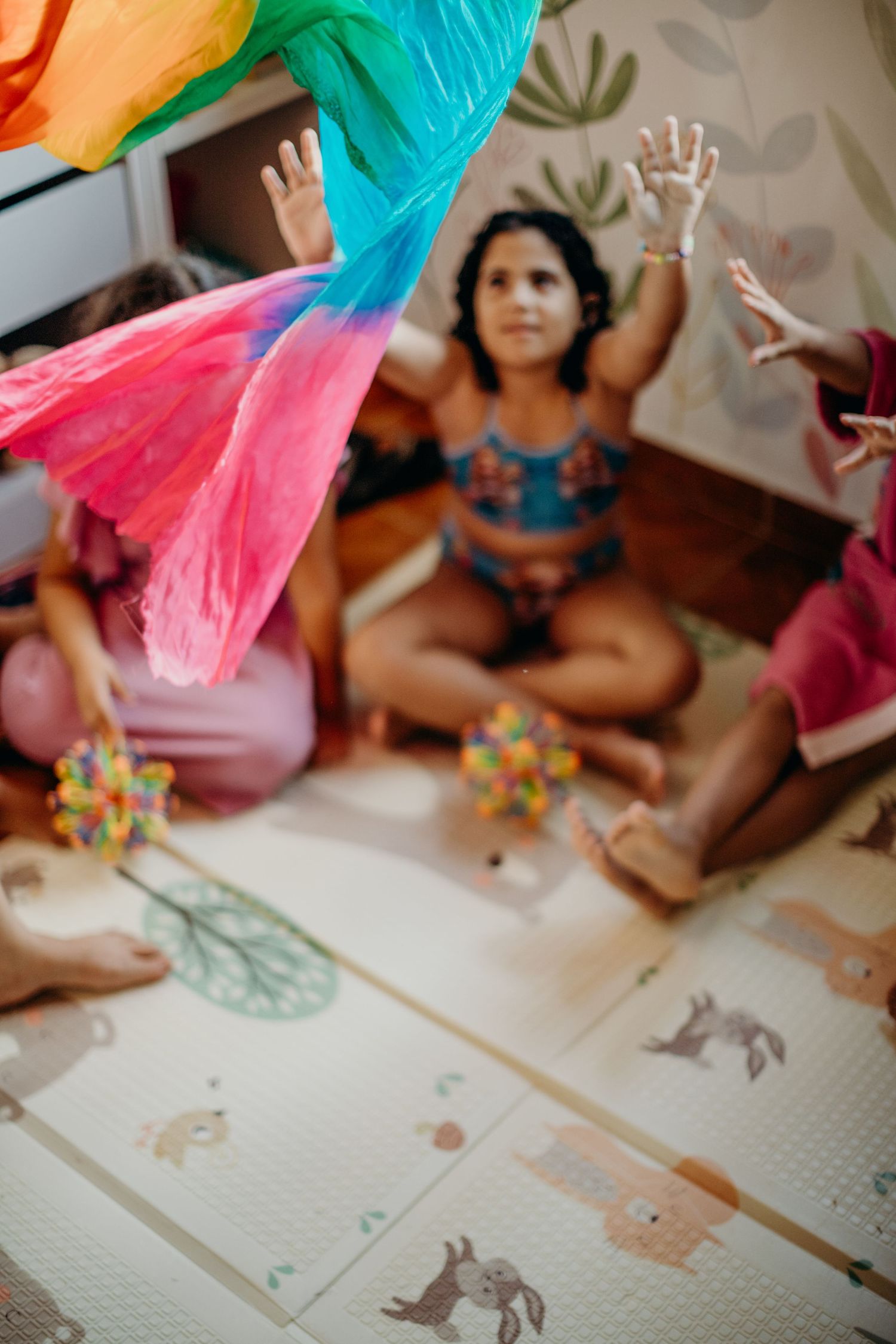 Rainbow-colored fabric hangs above a play mat with animal illustrations.