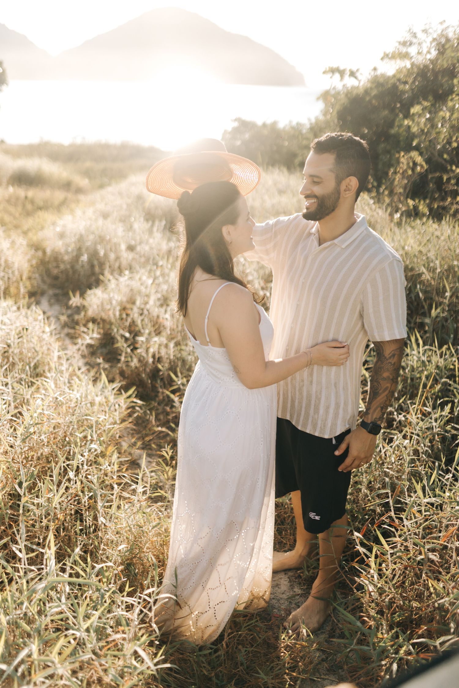 Couple enjoying playful moments together in a sunlit meadow during golden hour.