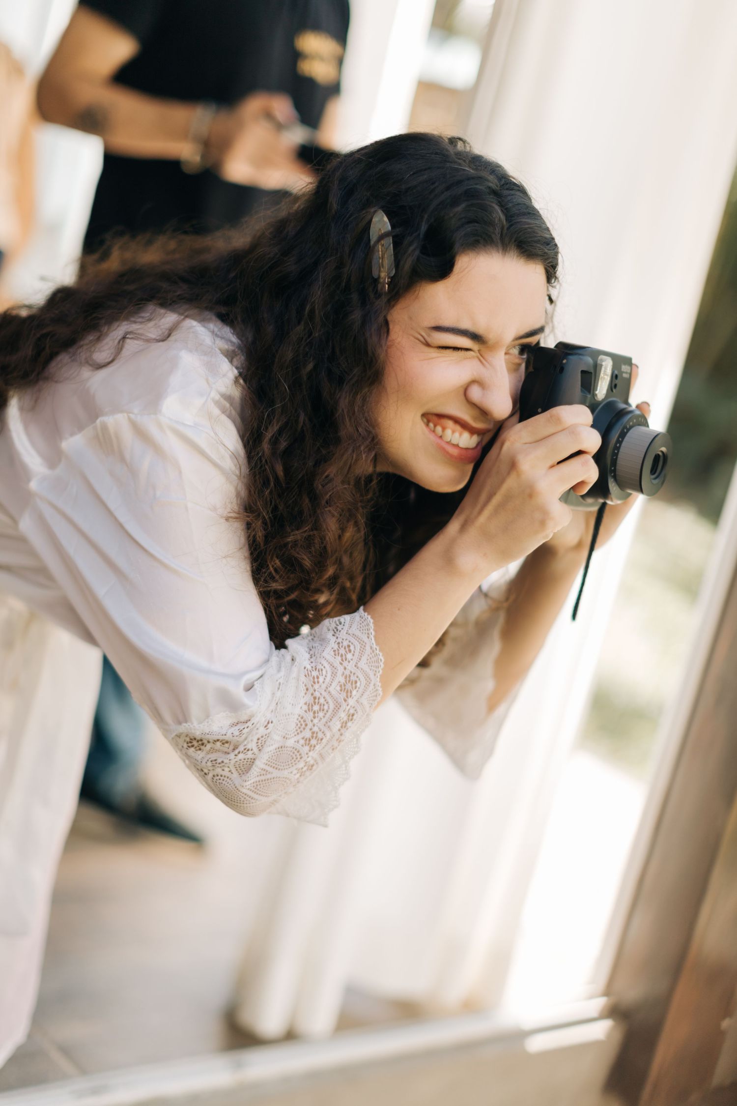 Candid moment of person using vintage camera while wearing white robe.