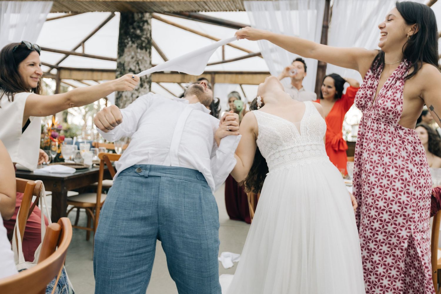 Wedding celebration features guests playing fun party game with bride at reception.