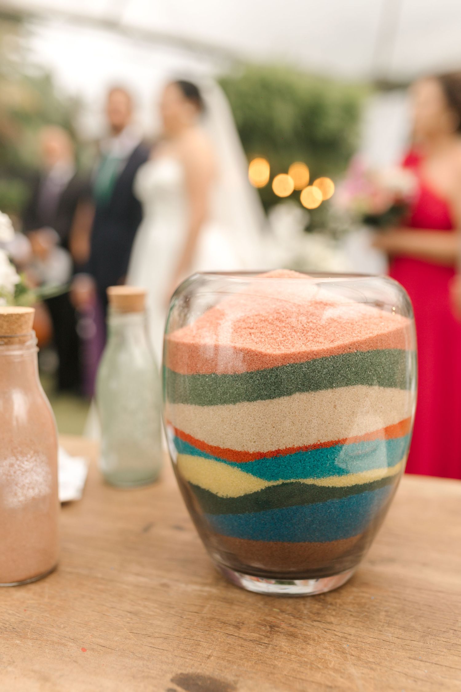 Close-up of layered sand art in glass vessels creating colorful patterns at wedding ceremony.