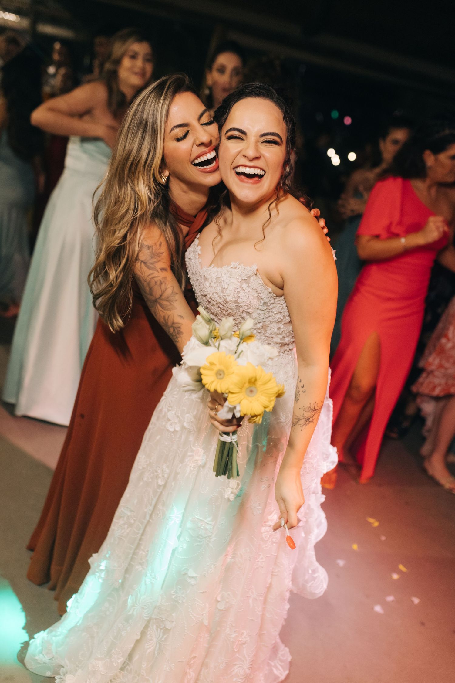 Joyful moment during wedding reception with bride holding yellow flowers.
