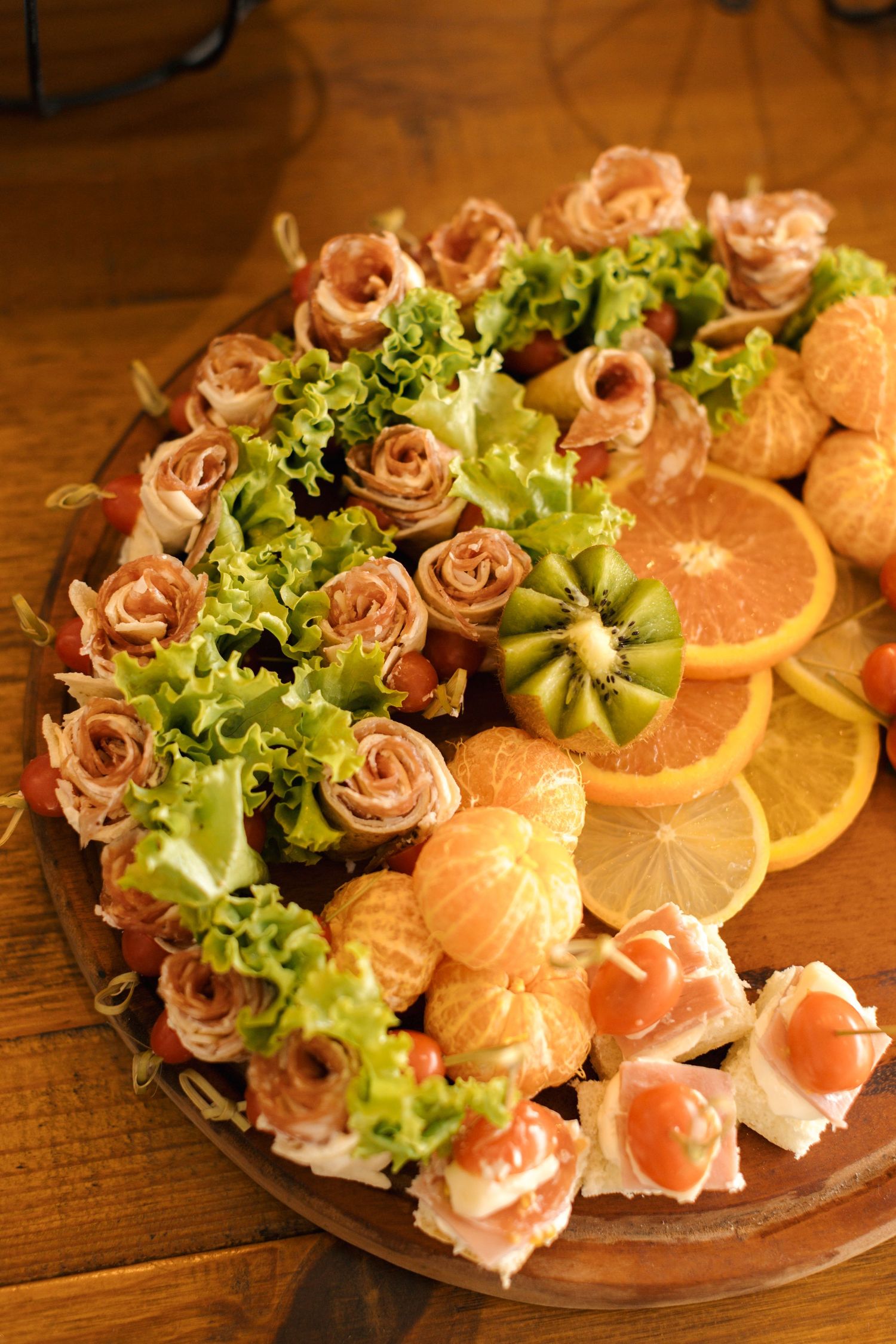 Elegant food platter with rolled meats, citrus slices, and lettuce arranged in decorative pattern.