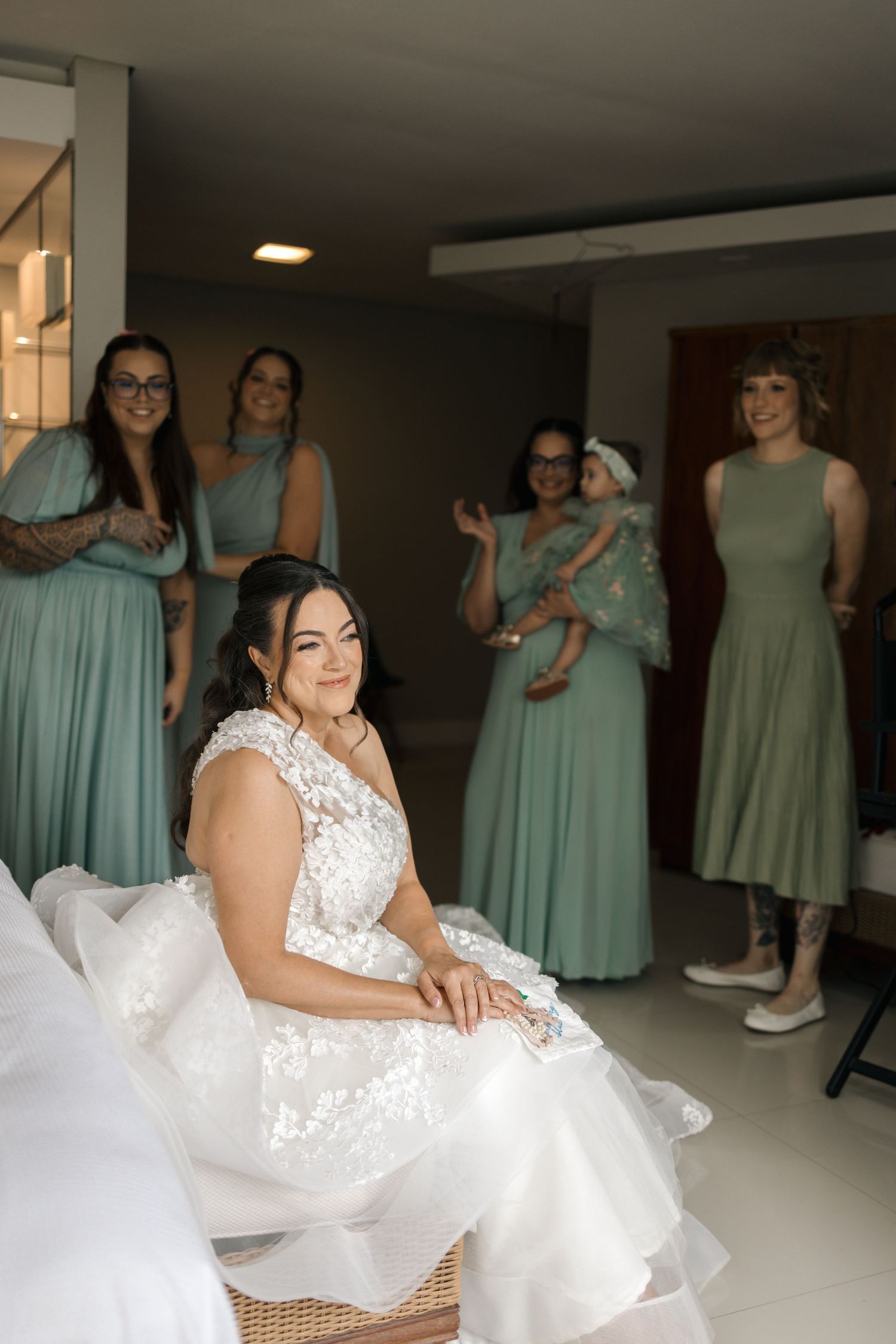 Bridesmaids in mint green dresses surround a bride in a white lace gown.
