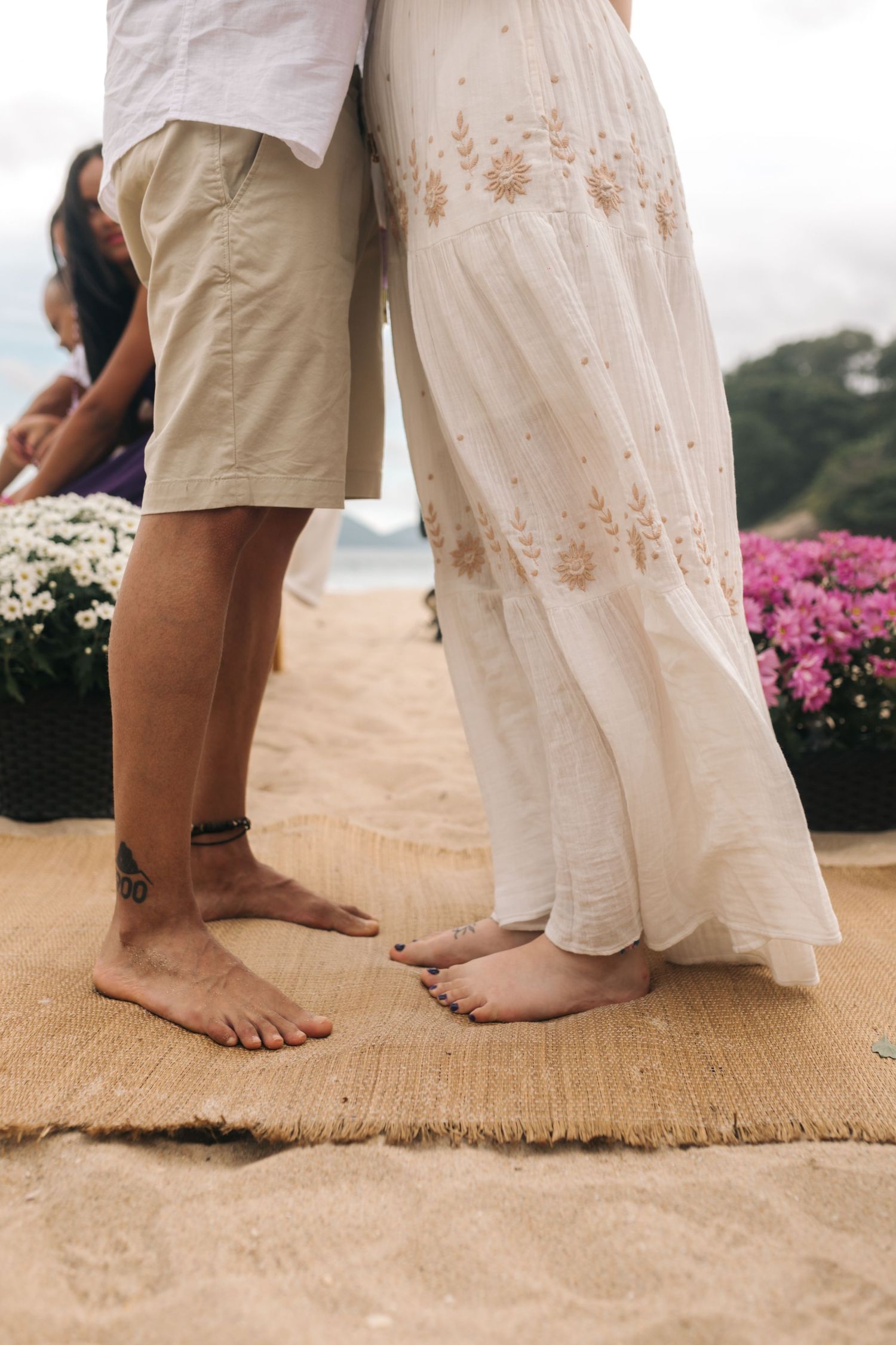 Bare feet of a couple standing on burlap runner during beach wedding ceremony.